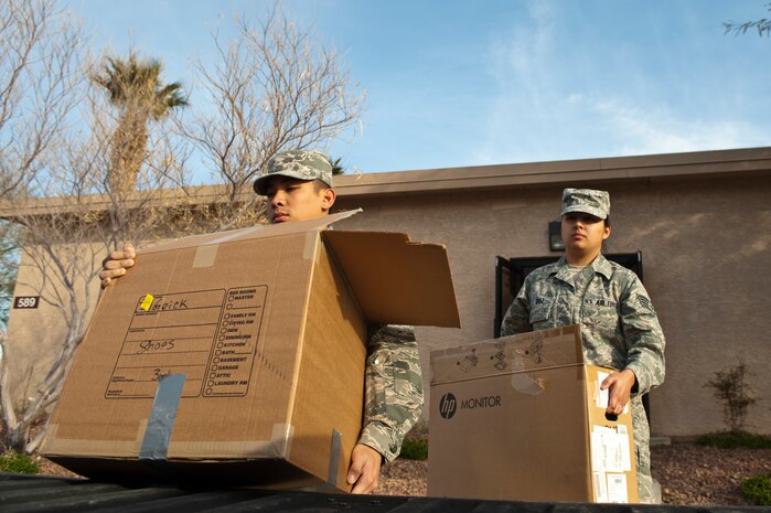 (Left) Airman 1st Class Jason Quiblat, 99th Communications Squadron circuit actions technician, and (right) Staff Sgt. Lourdes Diaz, 99th CS NCO in charge of circuit actions, move boxes from building 589 Feb. 18, 2014, at Nellis Air Force Base, Nev. Communications Focal Point, executive communications, COMSEC program, wing information assurance and the personal wireless communications systems work centers in the 99th CS are  moving into building 907. (U.S. Air Force photo by Senior Airman Christopher Tam)
