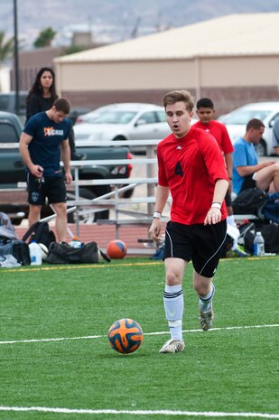 Tyler Robinson, number four and Nellis Air Force Base soccer team mid-fielder, runs with and dribbles a soccer ball down the field Feb. 15, 2014, at the soccer field behind the Warrior Fitness Center at Nellis AFB, Nev. During the soccer game, 11 players are allowed on the field from each team during play with two teams competing from Nellis AFB and one team from Edwards AFB in the tournament. (U.S. Air Force photo by Airman 1st Class Jake Carter)