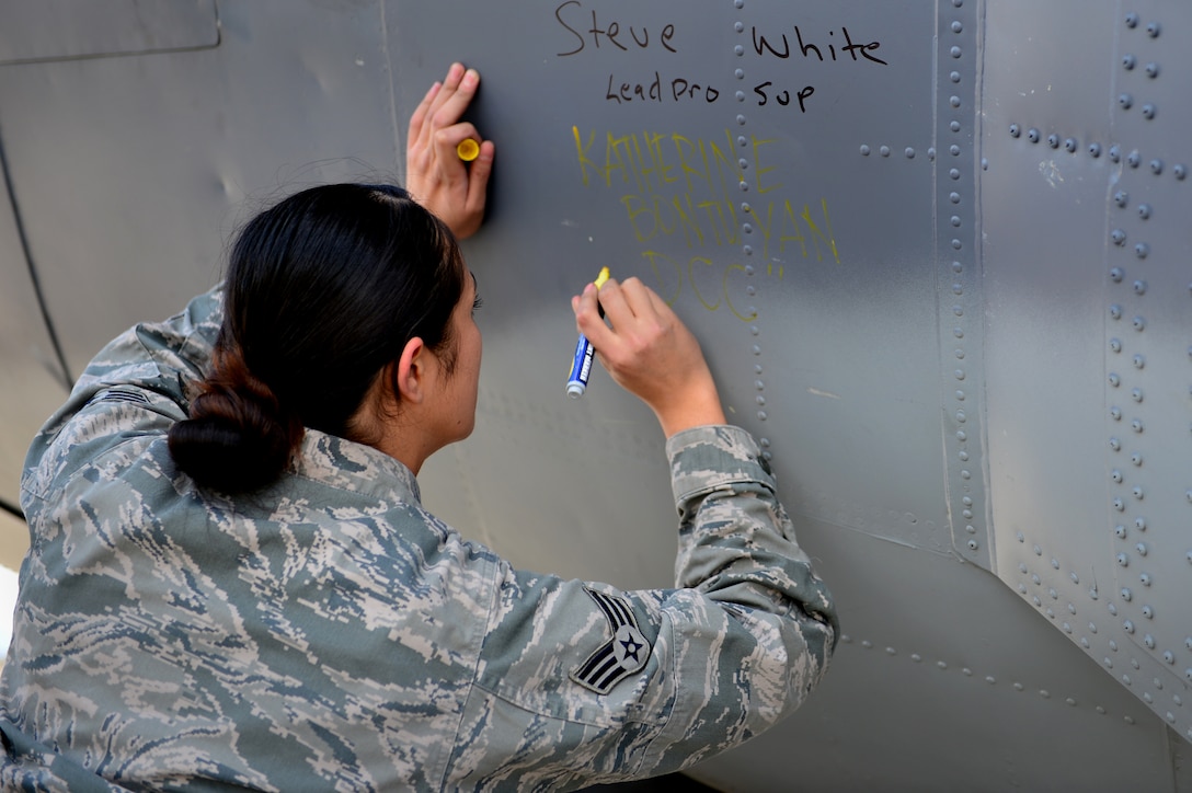U.S. Air Force Senior Airman Katherine Bontuyan, 27th Special Operations Aircraft Maintenance Squadron dedicated crew chief for "Bad Company" signs her name on the AC-130H Spectre gunship Bad Company after landing at Davis-Monthan Air Force Base, Ariz., Feb. 7, 2014. As the dedicated crew chief, Bontuyan has held the sole responsibility of ensuring that Bad Company was in tip top working condition in order to provide close air support, air interdiction and force protection for special operations forces when necessary. (U.S. Air Force photo/ Senior Airman Eboni Reece)