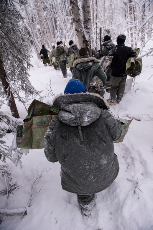 U.S. Air Force and U.S. Coast Guard members walk through the woods during Artic Survival School training Feb. 6, 2014, Eielson Air Force Base, Alaska. The training included building a shelter, starting a fire, setting up traps and using different types of smoke signals and flares. (U.S. Air Force photo by Senior Airman Joshua Turner/Released)