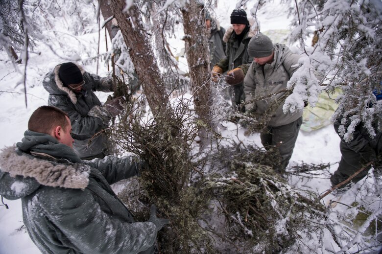 U.S. Air Force and U.S. Coast Guard members gather materials to start a fire during Artic Survival School training Feb. 6, 2014, Eielson Air Force Base, Alaska. Starting a fire from scratch was one of the many skills taught during “Cool School.” (U.S. Air Force photo by Senior Airman Joshua Turner/Released)