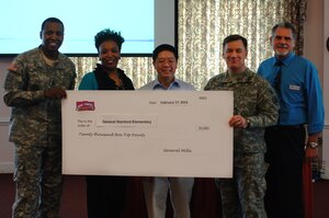 Representatives from the General Mills Box Tops for Education program present a check to General Stanford elementary school during the Volunteer of the Quarter ceremony hosted by U.S. Army Col. William Galbraith, 733rd Mission Support Group commander, at Fort Eustis, Va., Feb. 19, 2014. The school raised 20,000 box top points through cereal boxes and other General Mills food item box tops collected, which will be given to the school in a form of monetary donation. (U.S. Air Force photo by Senior Airman Teresa Aber/Released)
