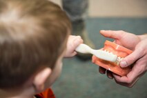 Minot Air Force Base Dental Clinics celebrate National Children's Dental Health Month with community outreach to the Child Development Center. Dental technicians from the Dental Clinic teach children from preschool class how to hold and properly brush their teeth using a model. Over 580 children were educated on proper dental hygiene.