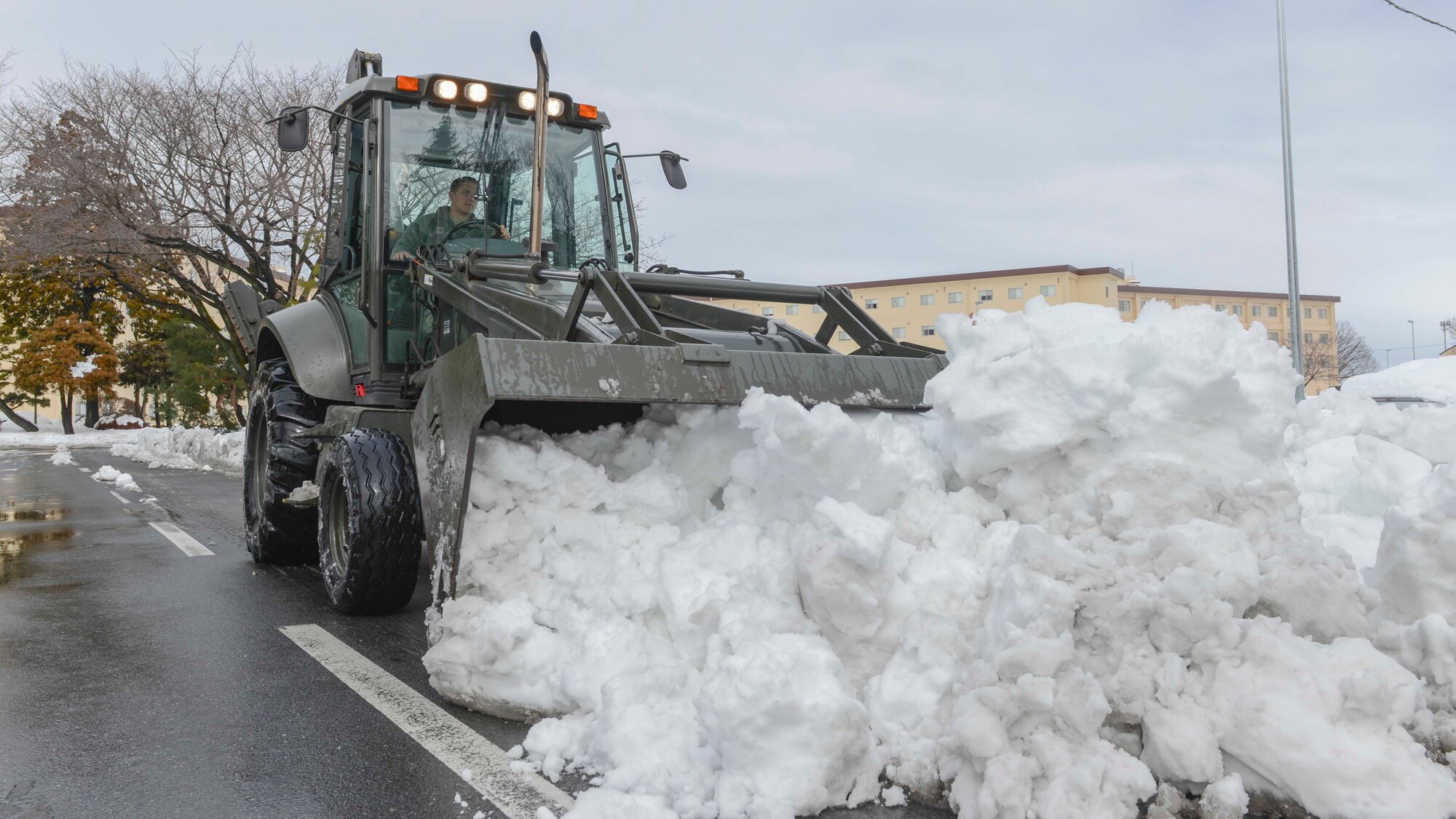 An Airman operates a snow removal vehicle to clear the roads at Yokota Air Base, Japan, Feb. 15, 2014.  Members of 374th Civil Engineer Squadron and Logistic Readiness Squadron worked feverishly to get the base operational.  (U.S. Air Force photo by Airman 1st Class Soo C. Kim / released)
