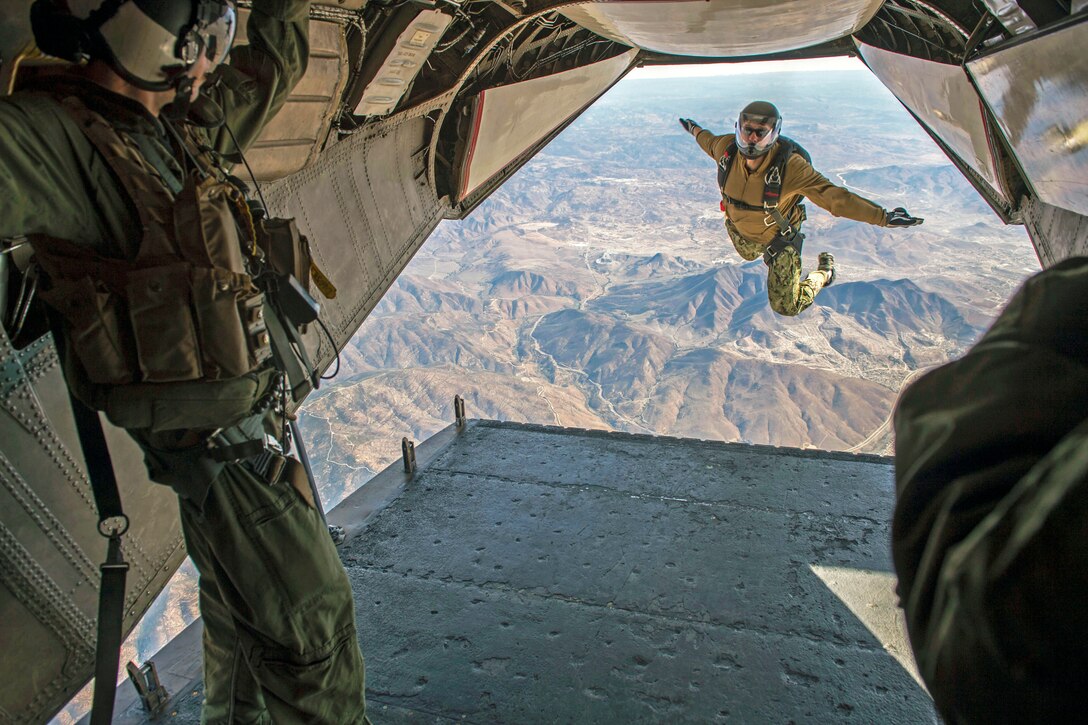 Navy Petty Officer 2nd Class Daniel Russell, left, watches as Navy Petty Officer 1st Class Nicholas Casamassa jumps from a C2-A Greyhound aircraft during jump requalification in San Diego, Feb. 11, 2014. Requalification included static line and free fall parachute jumps conducted by Explosive Ordinance Disposal Training and Evaluation Unit 1.