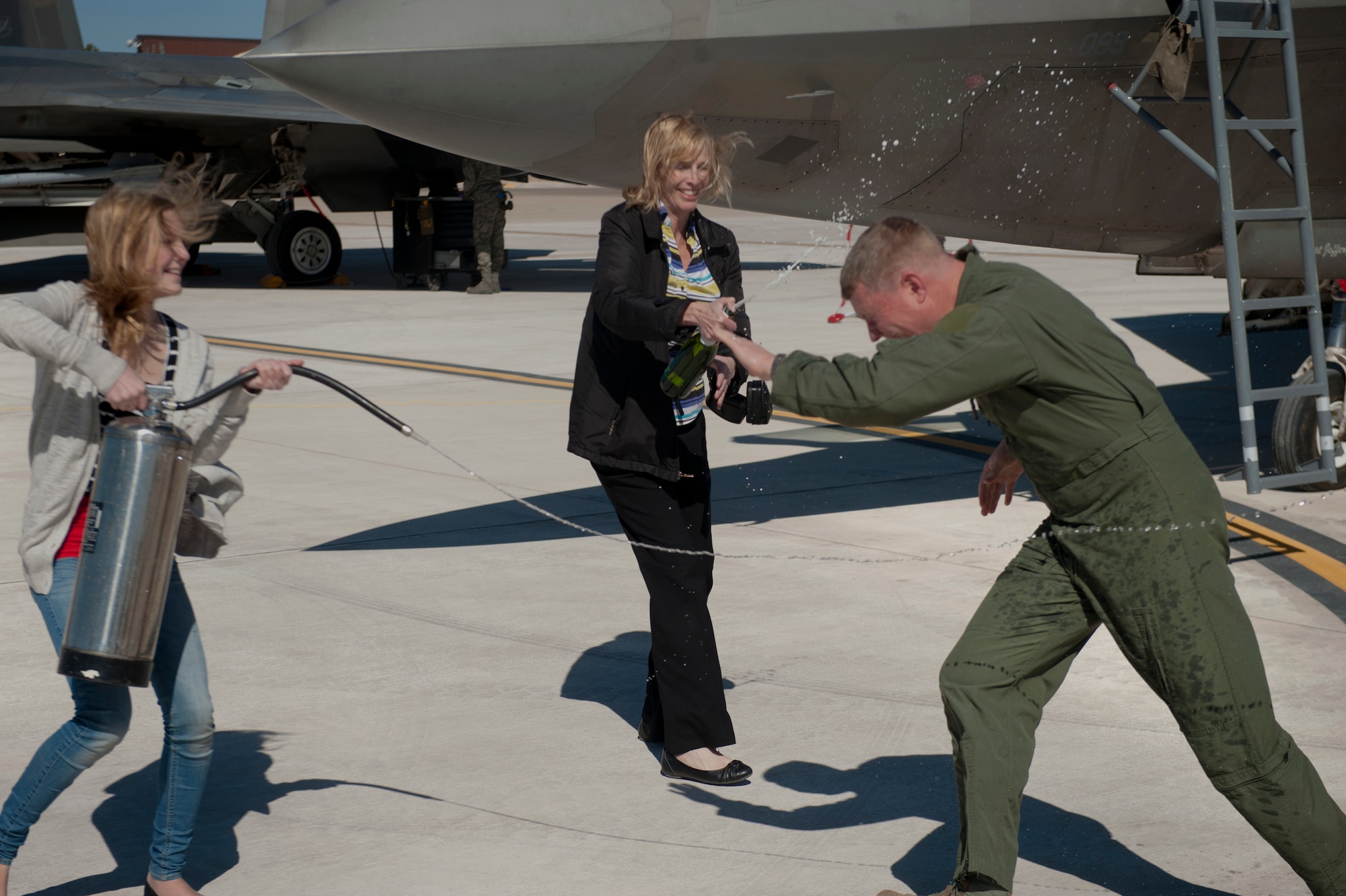 Nicole Croft and Vicki Croft spray Col. Andrew Croft, 49th Wing commander, after landing from the final F-22 Raptor four-ship tactical sortie flown at Holloman Air Force Base, N.M., Feb. 20. The 7th Fighter Squadron and members of the Holloman community celebrated this sortie before the F-22s depart for Tyndall Air Force Base, Fla., in early April. (U.S. Air Force photo by Airman 1st Class Aaron Montoya / Released)