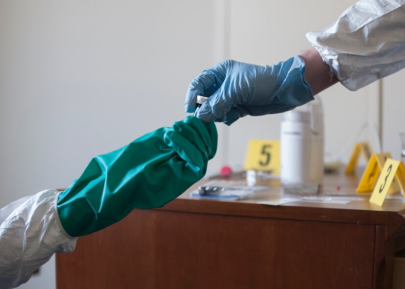 (Right to left) Capt. Andrew Bostic, 374th Aerospace Medicine Squadron chief of operation for bioenviromental engineering, hands a sample of simulated unknown substances to Senior Airman Luke Luallin, 374th Civil Engineer Squadron emergency management technician, during a hazardous material training exercise at Yokota Air Base, Japan, Feb. 20, 2014.The primary purpose of the exercise was joint crime scene preservation training among emergency management, bioenvironmental engineers, fire department, security forces, medical technicians and Air Force Office of Special Investigations to ensure minimal scene disturbance while completing presumptive identification, sampling and evidence collection.(Japan Air Self Defense Force photo by Tech. Sgt. Fumiaki Nishihara/released)