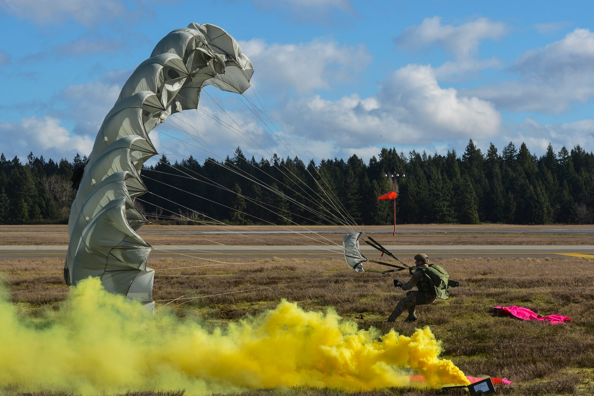 Staff Sgt. Brent Thornton, 22nd Special Tactics Squadron combat controller works to corral his parachute after landing in high winds near the echo ramp on McChord Field, Feb. 12, 2014 at Joint Base Lewis-McChord, Wash. Parachuting airmen can judge wind speeds base on a “V” pointing in the wind’s direction and from popped smoke provided by combat controllers on the ground. (U.S. Air Force photo/Staff Sgt. Russ Jackson)
