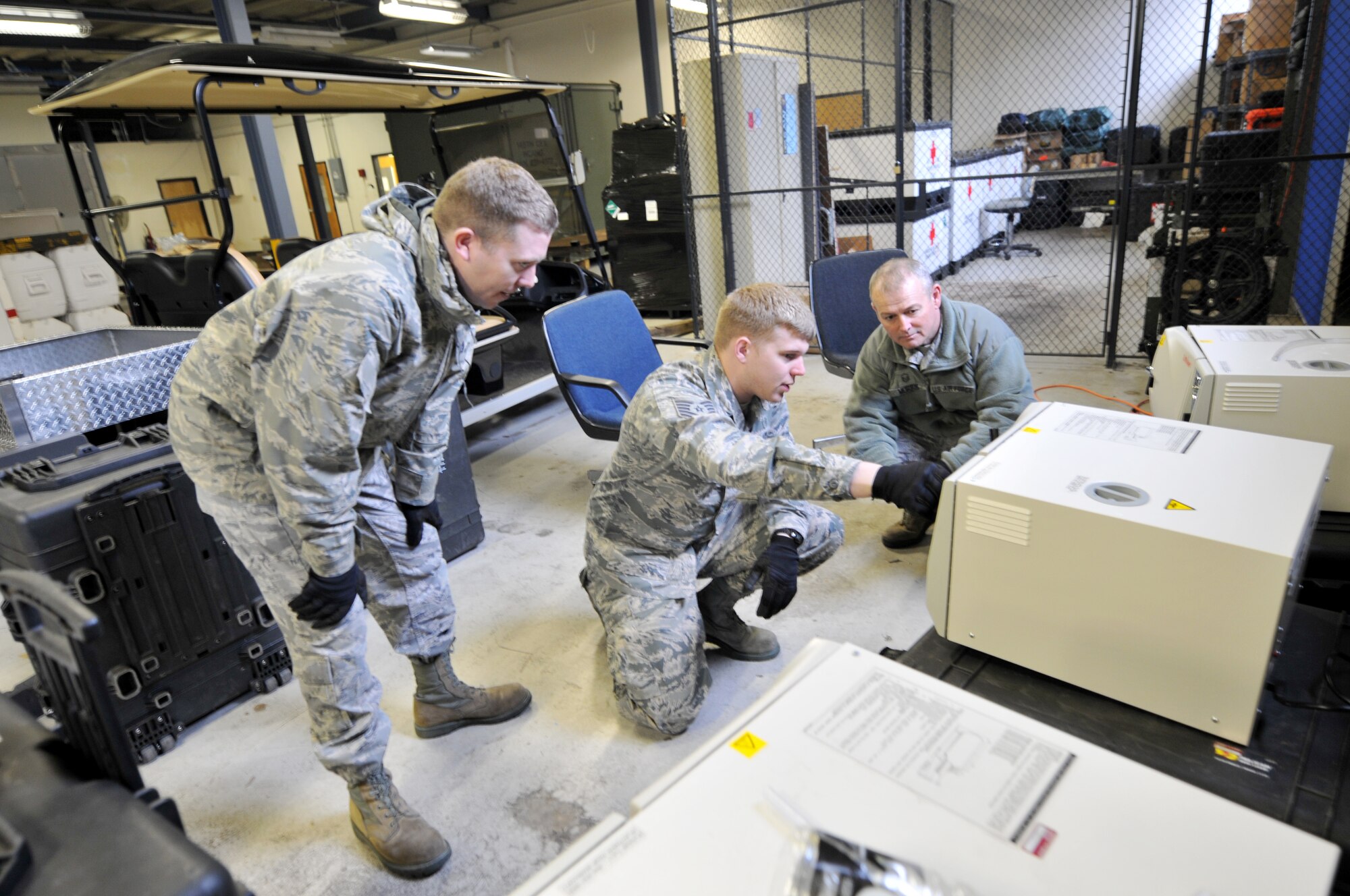 U.S. Air Force Tech. Sgts. Jonathon Jonas and Paul Talbot and Master Sgt. Rubin Morris, members of the 156th Aeromedical Evacuation Squadron, try to stay warm and continue the mission as the second winter storm of the season hits the Carolinas, February 12, 2014.  Jonas, Talbot and Morris go over operating procedures and safety precautions on sterilizers used for medical equipment at the North Carolina Air National Guard base, Charlotte Douglas Intl. airport, as part of a joint service team preparing medical equipment for a mission in Abbeville, Louisiana.  The 145th AW will be building five pallets that will be flown by 145th AW C-130 aircraft.  Joint service military will provide medical, dental and optometry care to residents of Abbeville, Louisiana and surrounding areas in support of “Cajun Care.” (U.S. Air National Guard photo by Master Sgt. Patricia F. Moran, 145th Public Affairs/Released)