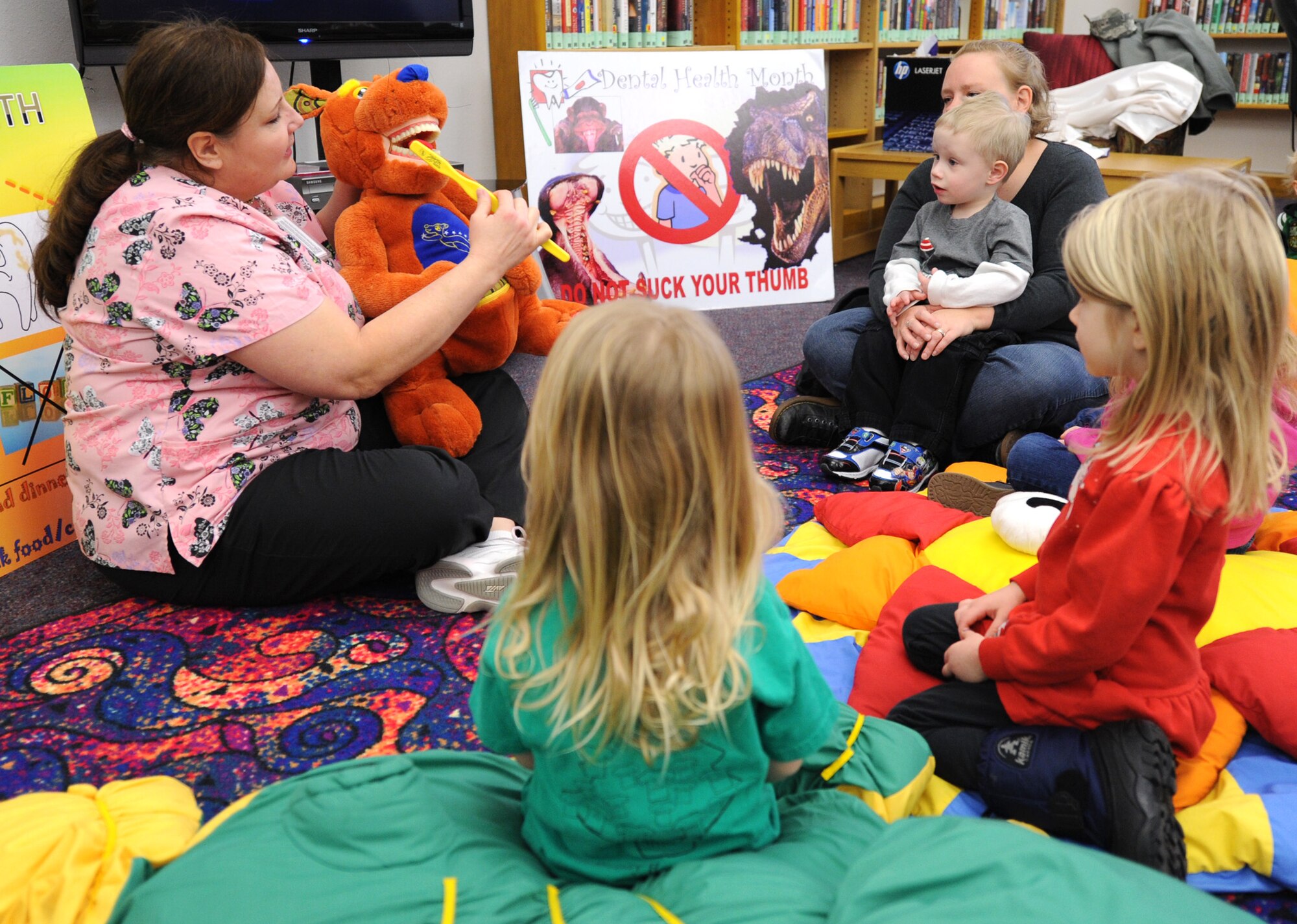 Mercy Padgett, 341st Medical Operations Squadron supervisory dental hygienist (left), demonstrates to children how to properly brush teeth at the Malmstrom Air Force Base Library on Feb. 18. Malmstrom Dental Flight members also visited the youth center and Loy Elementary School throughout the month of February as part of Children’s Dental Health Month. (U.S. Air Force photo/Senior Airman Katrina Heikkinen) 

