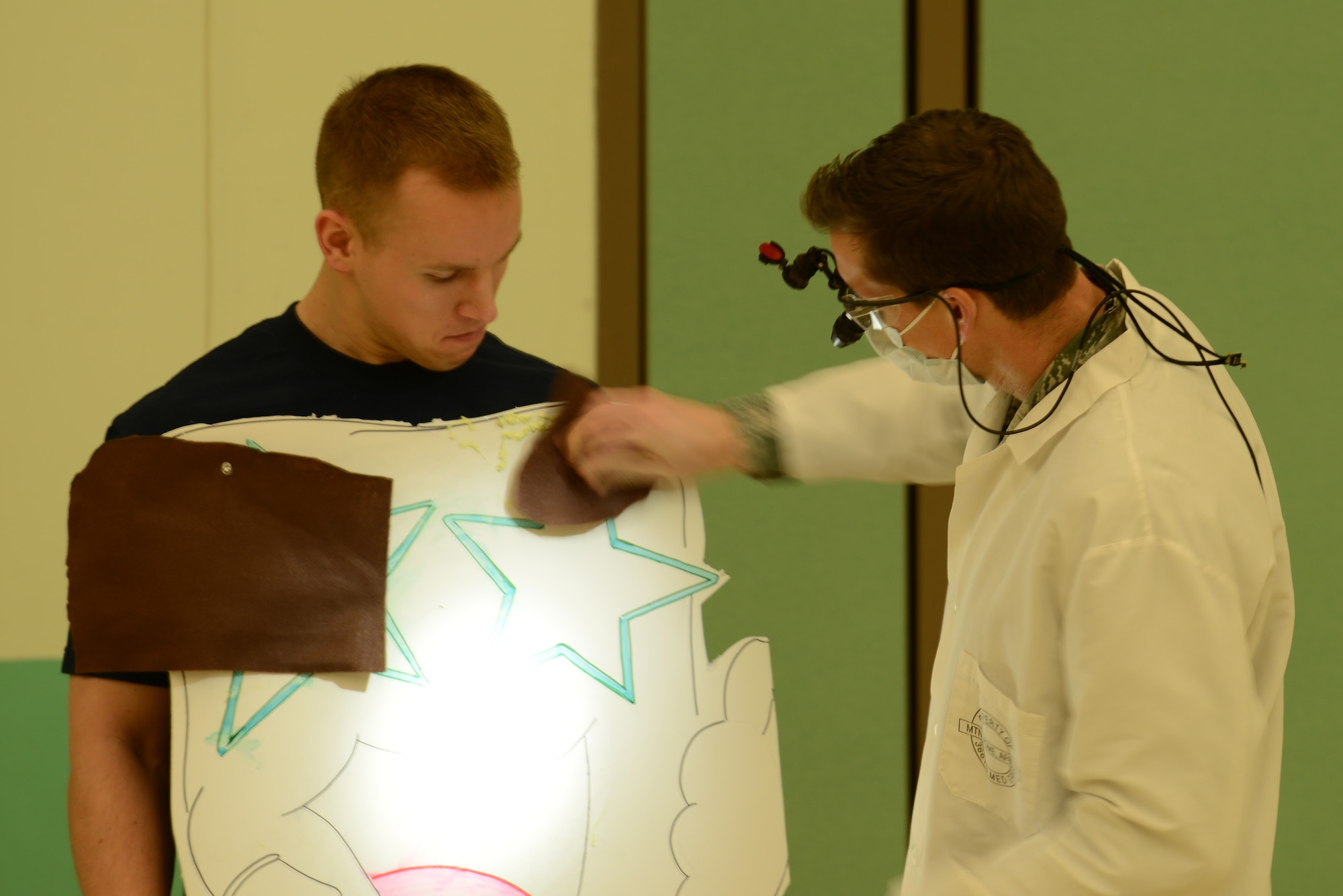 Portraying a tooth is Airman 1st Class Thomas Bernhardt, 366th Aerospace Medicine Squadron dental technician, while Capt. Jacob Powell, 366th AMDS general dentist, performs a routine inspection during a skit Feb. 19, 2014, at Mountain Home Air Force Base, Idaho. Members of the dental flight performed for childen to showcase the importance of dental hygiene especially at an young age. The skit emphisized that developing good dental habits at an early age and scheduling regular visits helps children get a good start on a lifetime of healthy teeth and gums. (U.S. Air Force photo by Senior Airman Benjamin Sutton/Released)

