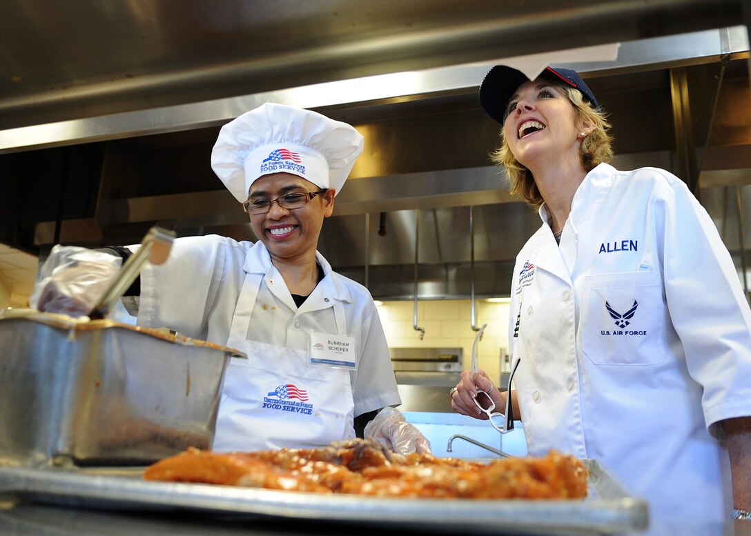 Jara Allen evaluates Bunrham Scherer as she prepares ribs for the Love Fest lunch service Feb. 14 at Freedom Hall Dining Facility on Joint Base Andrews, Md. Two evaluators from the National Restaurant Association make their third stop of a world-wide tour for the Air Force’s 58th Annual Hennessy Trophy Awards Program Competition. Scherer is a Suns Equality first cook and Allen is the International Military Community Executives Association executive director.  (U.S. Air Force Photo/Staff Sgt. Nichelle Anderson)