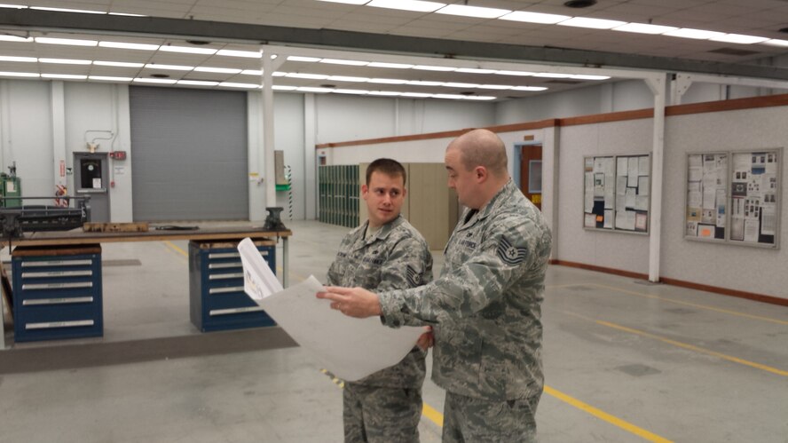 Tech. Sgt. Travis Waskom, aircraft structural maintenance section chief, left, and Tech. Sgt. Steven Farley, assistant section chief, look over plans for placing equipment to create maximum efficiencies in the 552nd Maintenance Squadron’s Fabrication Flight after a recent recapitalization provided additional floor space within Bldg. 230. (Air Force photo by Tech. Sgt. Mark Smith)