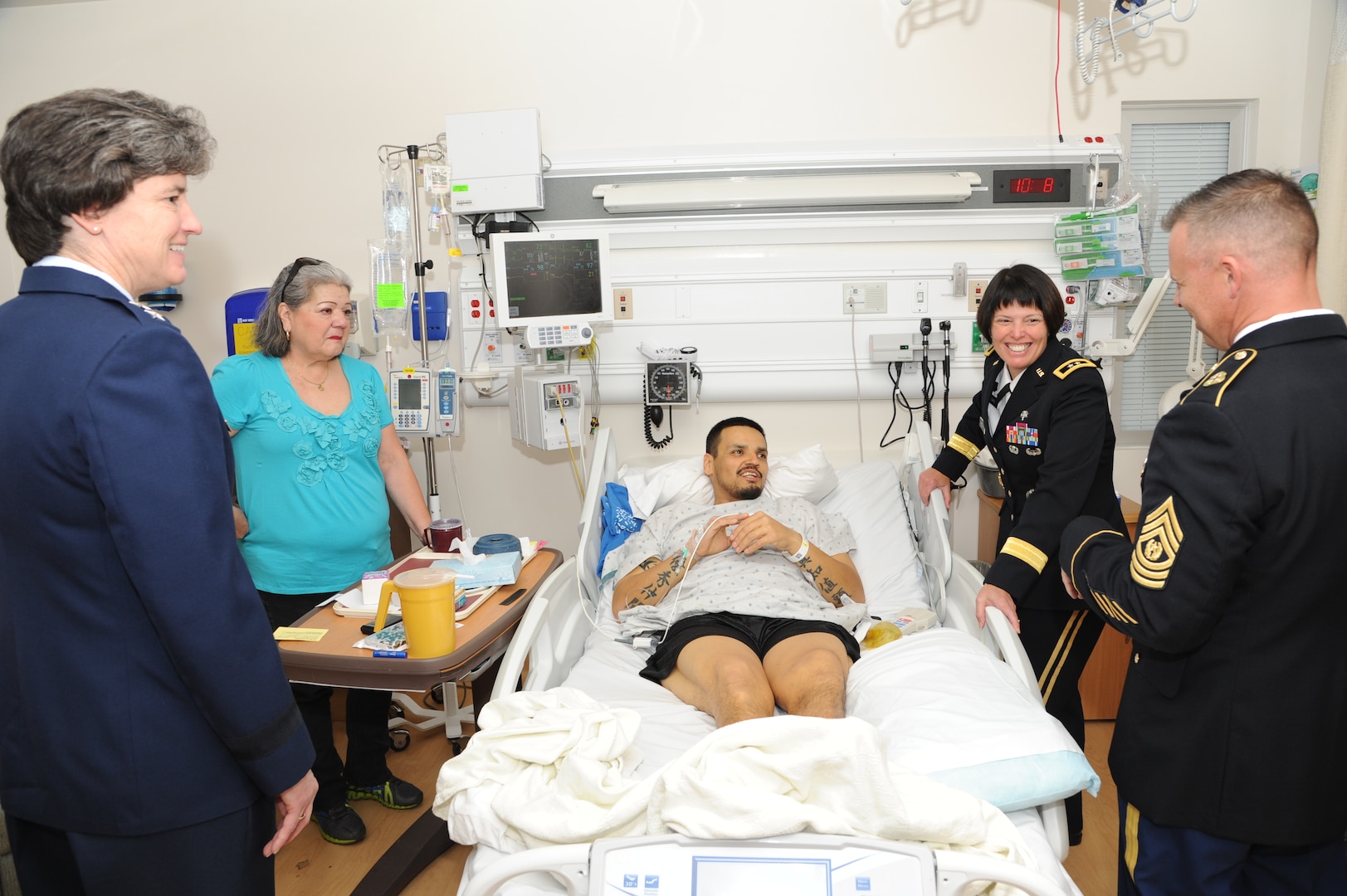 Maximiliano M. Martinez, Army veteran, center, and his mother, Olga Alcoser, back left, are greeted by Army Maj. Gen. Jimmie Keenan, Southern Regional Medical Command commander, back right, Air Force Maj. Gen. Peggy Poore, Air Force Personnel Center commander, left, and Army Command Sgt. Maj. Jayme D. Johnson, Southern Regional Medical Command command sergeant major, right, during the 2014 National Salute to Veteran Patients Feb. 14 at the Audie Murphy VA Hospital in San Antonio.  The Joint Base San Antonio military ambassadors and JBSA military leaders were on hand to distribute valentines and visit with veteran patients. Veterans administration facilities across the United States pay tribute to veteran patients annually during this week-long salute. (U.S. Air Force photo by Melissa Peterson)