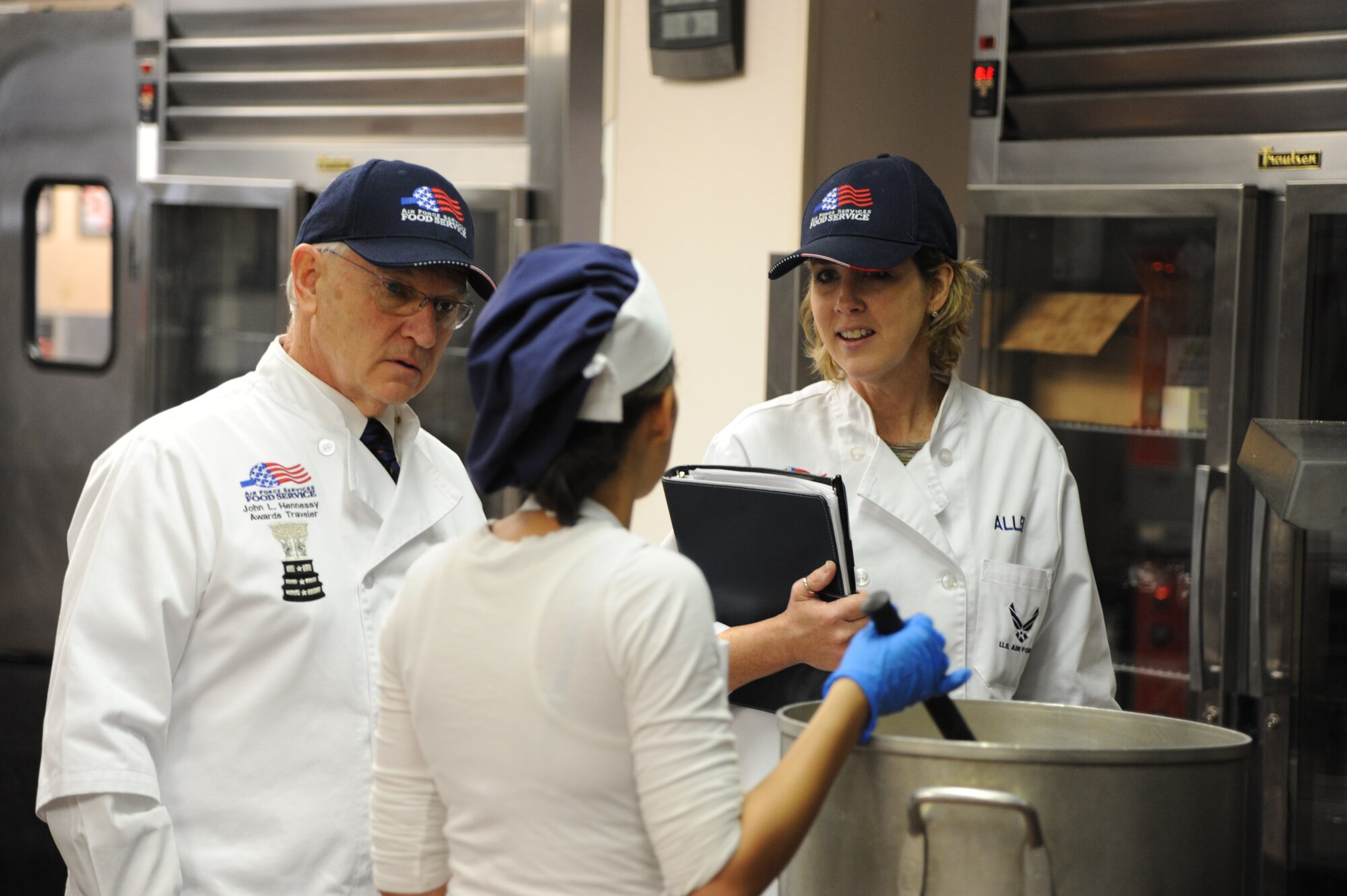 Joseph M. De Rosa and Jara N. Allen, Hennessy Awards evaluators, speak to Senior Airman Kara Cantone, 87th Force Support Squadron Food Service cook from Harrisburg, Pa., during the Hennessy Award evaluation Feb. 12, 2014, at the Halvorsen Hall dining facility at Joint Base McGuire-Dix-Lakehurst, N.J. The Hennessy award is presented to the best food service program within the Air Force annually. (U.S. Air Force photo by Airman 1st Class Sean M. Crowe/Released)