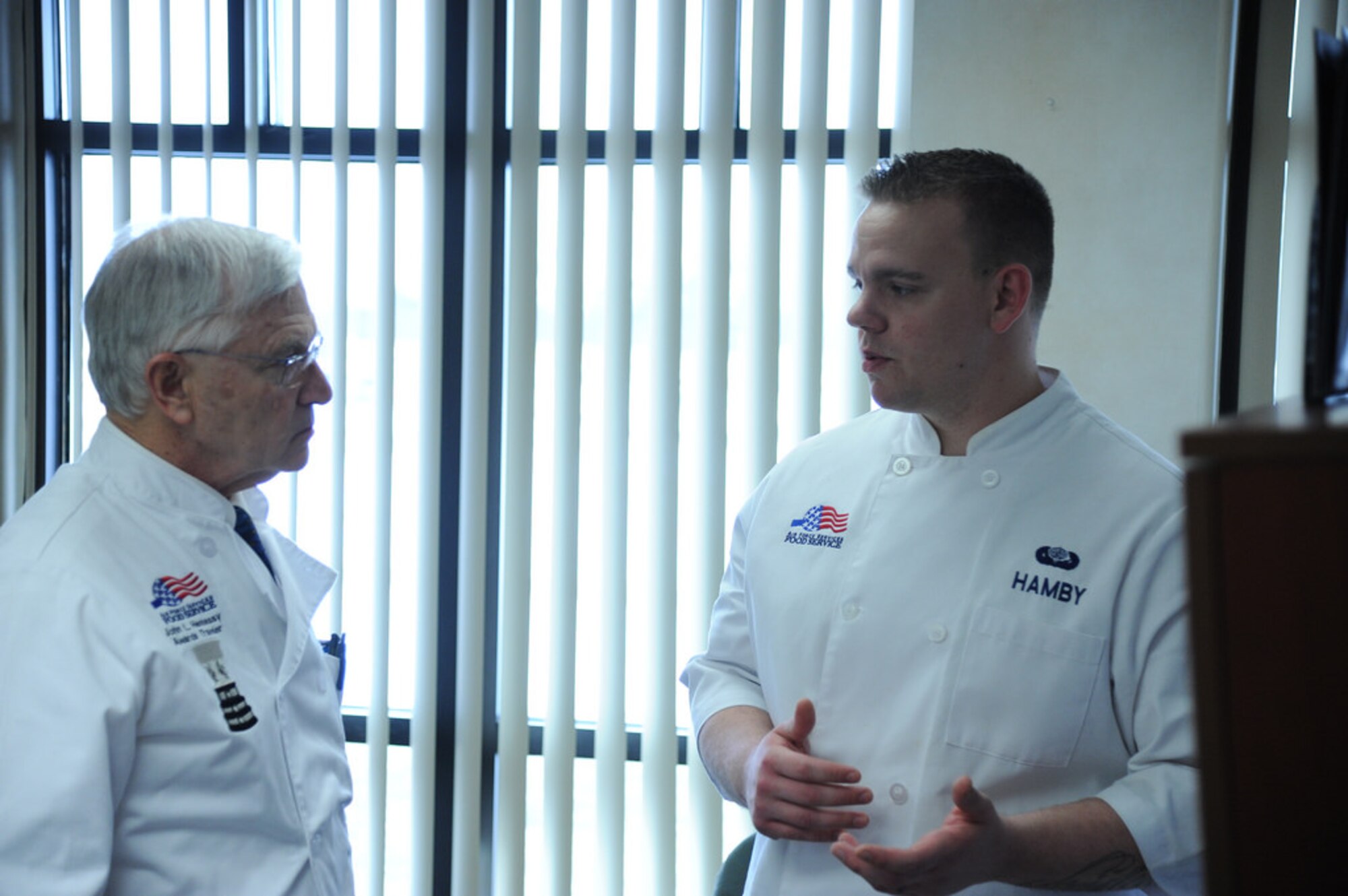 Joseph M. De Rosa, Hennessy Awards evaluator, speaks to Staff Sgt. James Hamby, 87th FSS Food Service accountant from Kelso, Wash., during the Hennessy Award evaluation Feb. 12, 2014, at the Halvorsen Hall dining facility at Joint Base McGuire-Dix-Lakehurst, N.J. The Hennessy award is presented to the best food service program within the Air Force annually. (U.S. Air Force photo by Airman 1st Class Sean M. Crowe/Released)