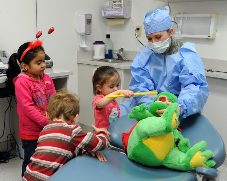 Staff Sgt. Amanda Perkins, 2nd Dental Squadron registered dental hygienist, uses Dudley the Dinosaur to teach children proper oral care at the 2nd DS on Barksdale Air Force Base, La., Feb. 14, 2014. Perkins gave a tour of her work station and allowed the children to play the role of a dentist to promote National Children's Dental Health Month. (U.S. Air Force photo/Senior Airman Joseph A. Pagán Jr.)