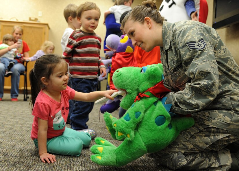 Staff Sgt. Amanda Perkins, 2nd Dental Squadron registered dental hygienist, uses Dudley the Dinosaur to teach children proper oral care at the 2nd DS on Barksdale Air Force Base, La., Feb. 14, 2014. Perkins gave every child the opportunity to brush Dudley's teeth to show them proper care. (U.S. Air Force photo/Senior Airman Joseph A. Pagán Jr.)