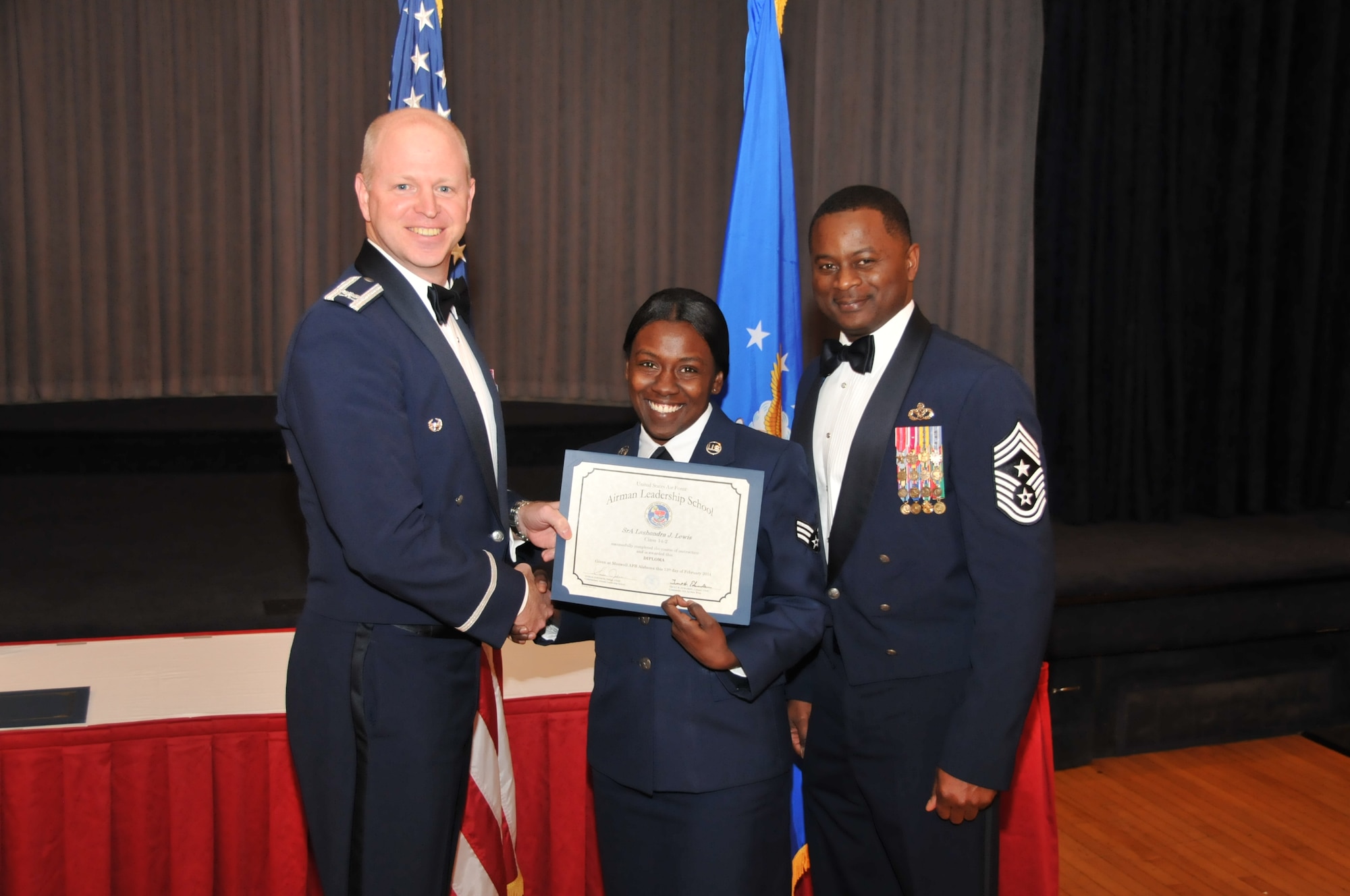 U.S. Air Force Col. Mark Ramsey, Vice Commander 42nd Air Base Wing, and Chief Master Sgt. Harry Hutchinson, Command Chief 42nd Air Base Wing, presents the Airman Leadership School graduating diploma to Senior Airman Lashondra Lewis, 187th Security Forces Squadron, at Maxwell Air Force Base, Ala., Feb. 13, 2014. Airman Leadership School teaches leadership and supervisory skills to Senior Airmen and is required for Airmen to become Noncommissioned Officers. (U.S. Air Force photo by Tech. Sgt. Matthew Garrett)