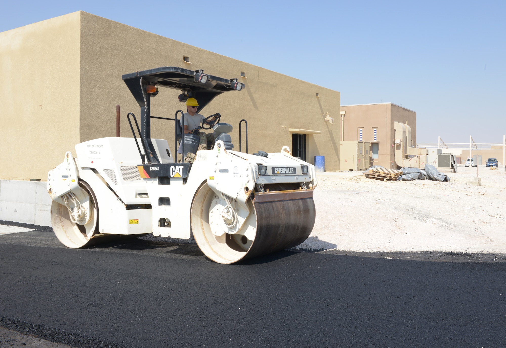 Senior Airman Arash Mozaffari rolls new asphalt for an access road at Al Udeid Air Base, Qatar, Feb. 19, 2014. The Contingency Aeromedical Staging Facility will house and provide medical care to wounded service members prior to medical evacuation. RED HORSE provides heavy repair and construction capabilities throughout the U.S. Air Forces Central Command area of responsibility. Mozaffari is a 557th Expeditionary Rapid Engineer Deployable Heavy Operational Repair Squadron Engineer heavy equipment operator deployed from Nellis Air Force Base, Nev., and a San Diego, native. (U.S. Air Force photo/Senior Airman Hannah Landeros)