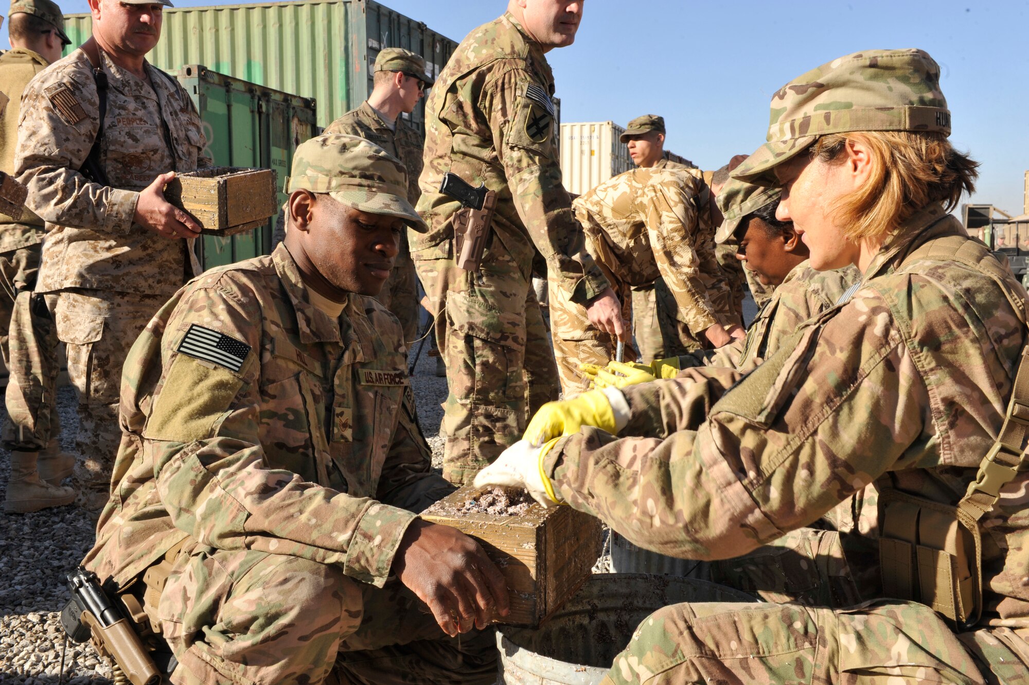 U.S. Service members pack a mixture of wet shredded paper and saw dust into wooden forms to make fire bricks at Camp Phoenix, Afghanistan, Feb. 16, 2014. Service members from all branches along with coalition partners all volunteered to make the fire starters that are later distributed to local Afghan families to use as a source of heat during cold weather.(U.S. Air Force photo by Senior Master Sgt. Gary J. Rihn/Released) 