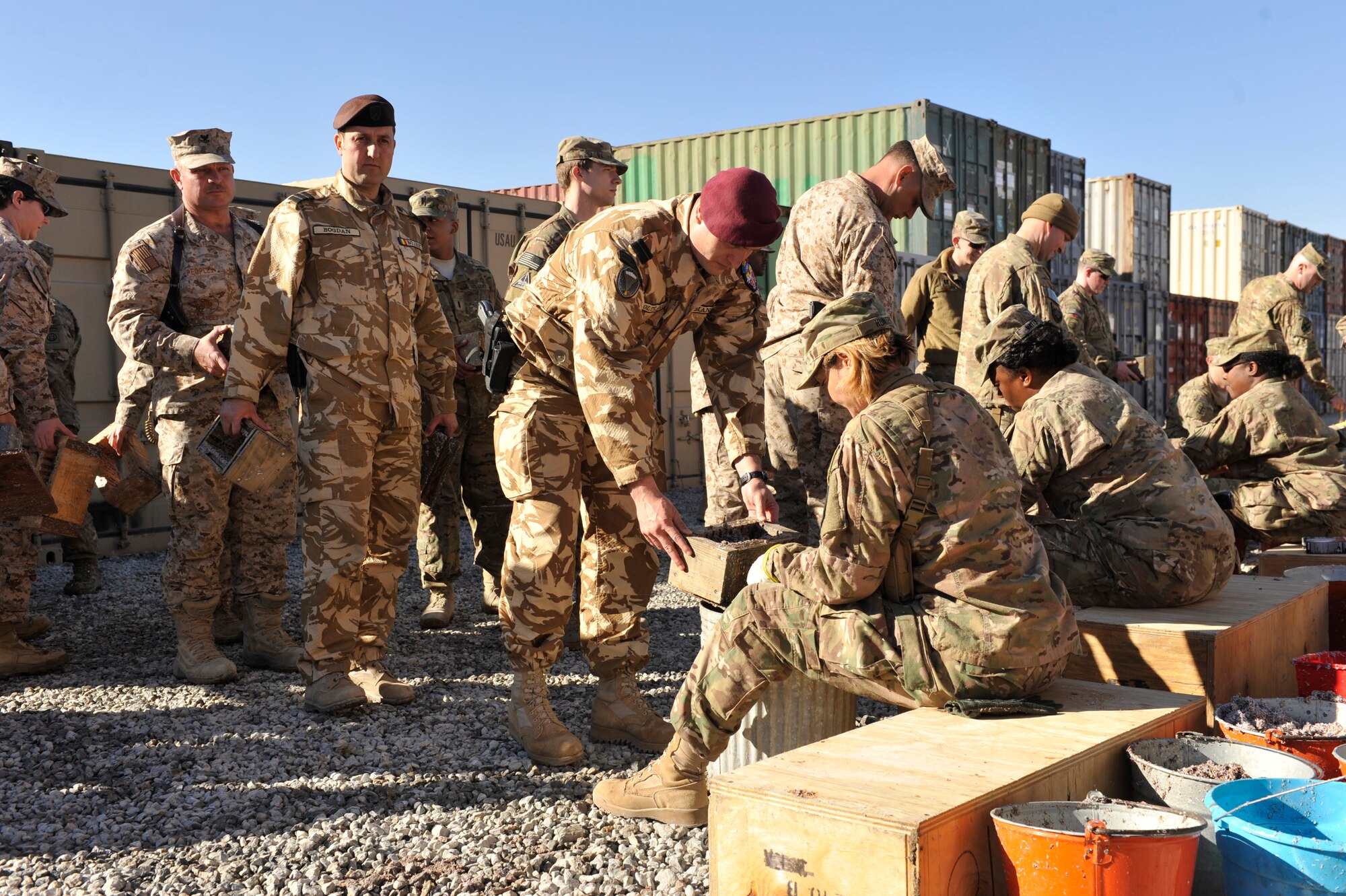 U.S. Service members pack a mixture of wet shredded paper and saw dust into wooden forms to make fire bricks at Camp Phoenix, Afghanistan, Feb. 16, 2014. Service members from all branches along with coalition partners all volunteered to make the fire starters that are later distributed to local Afghan families to use as a source of heat during cold weather.(U.S. Air Force photo by Senior Master Sgt. Gary J. Rihn/Released)