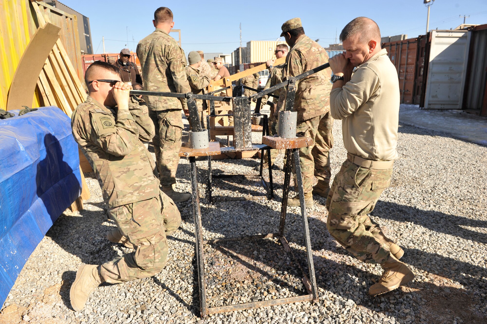 U.S. Service members pull down on levers that squeeze excess water from newly formed fire donuts, a mixture of wet shredded paper and saw dust that is placed into a mold, compressed and then dried, at Camp Phoenix, Afghanistan, Feb. 16, 2014. Service members from all branches along with coalition partners all volunteered to make the fire starters that are later distributed to local Afghan families to use as a source of heat during cold weather.(U.S. Air Force photo by Senior Master Sgt. Gary J. Rihn/Released)