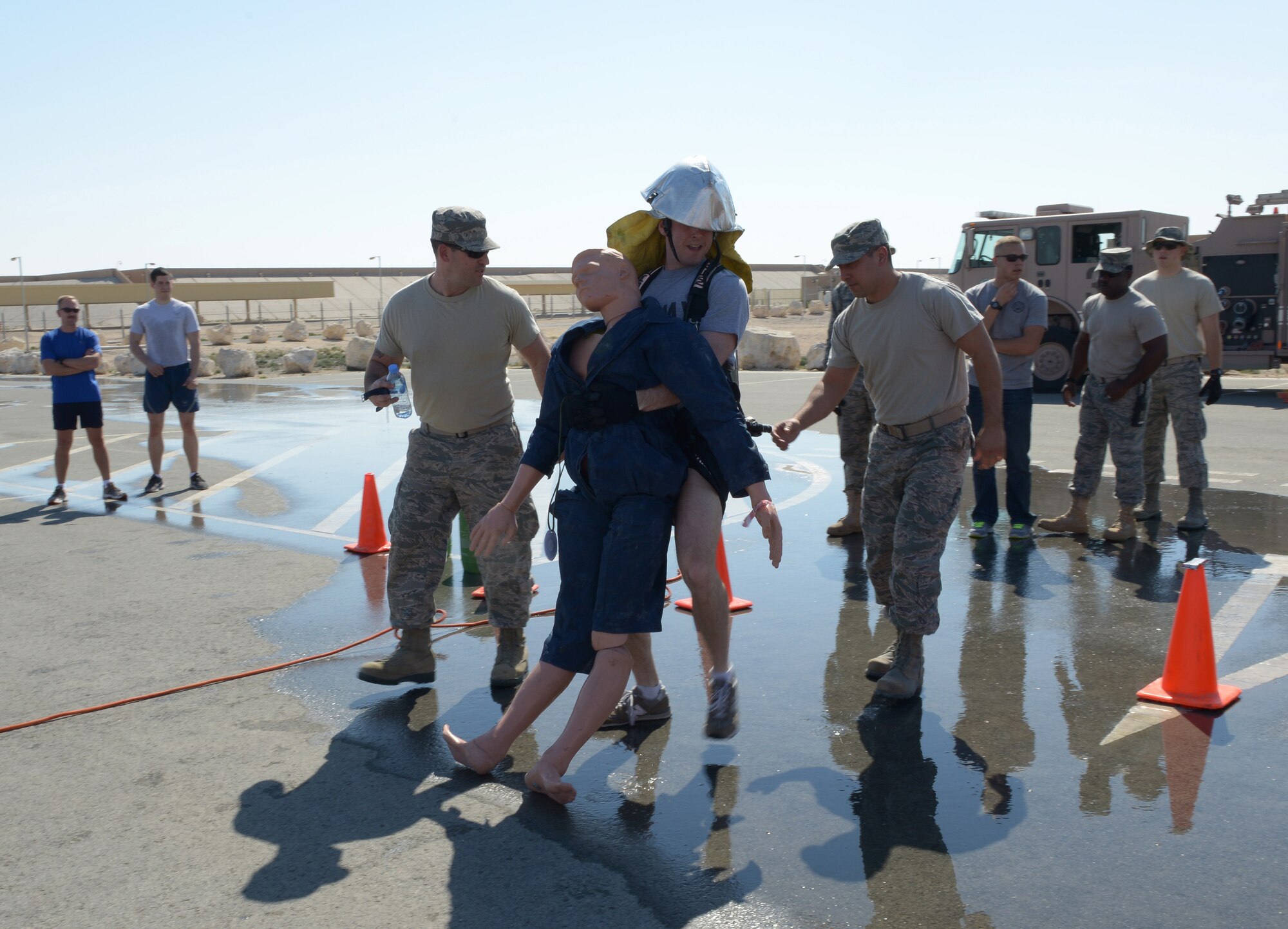 Firefighters from the 379th Expeditionary Civil Engineer Squadron spot a soldier during a fire muster competition at Al Udeid Air Base, Qatar, Feb. 15, 2014. The fire muster is an obstacle course that consists of seven stations which each team must complete in less than five minutes. Ten teams of four people competed in the fire muster with the winning team completing the course with a time of three minutes and 16 seconds. (U.S. Air Force photo/Senior Airman Hannah Landeros)