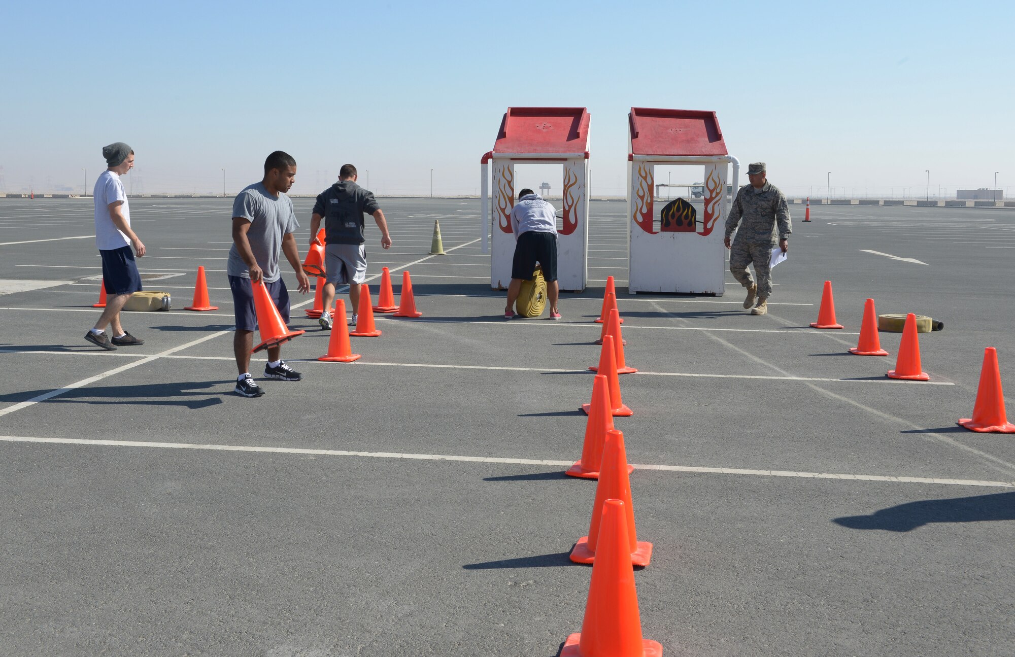 Firefighters from the 379th Expeditionary Civil Engineer Squadron set up for a fire muster at Al Udeid Air Base, Qatar, Feb. 15, 2014. The fire muster is an obstacle course that consists of seven stations which each team must complete in less than five minutes. Ten teams of four people competed in the fire muster; the winning team completed the course with a time of three minutes and 16 seconds. (U.S. Air Force photo/Senior Airman Hannah Landeros)