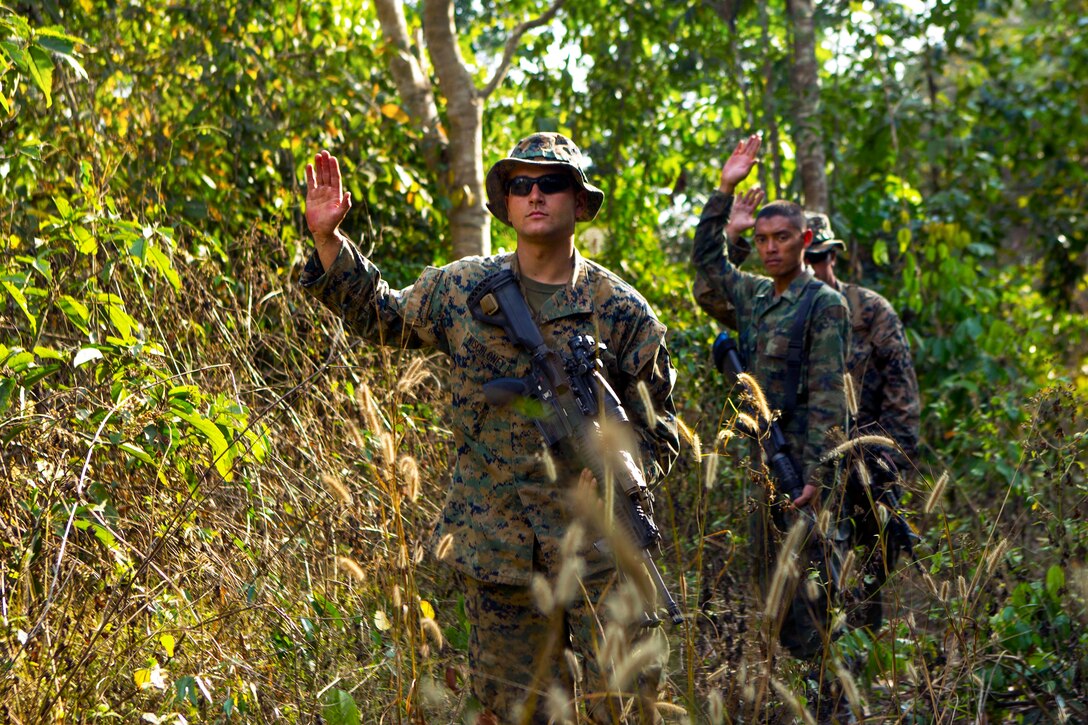 U.S. Marine Corps Lance Cpl. Justin D. Mischloney, foreground, uses hand and arm signals to halt following Thai and U.S. Marines participating in jungle patrol training evolution during Cobra Gold 2014 at Ban Chan Krem, Thailand, Feb. 12, 2014. Mischloney is assigned to Lima Company, 3rd Battalion, 1st Marine Regiment, currently attached to 4th Marines, 3rd Marine Division, 3rd Marine Expeditionary Force.