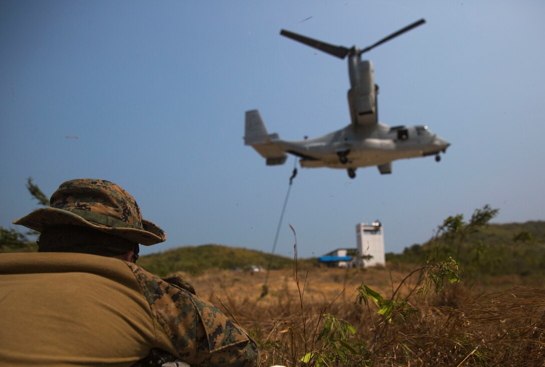 A U.S. Marine watches Royal Thai, Republic of Korea and U.S. Marines fast rope from an MV-22B Osprey at Hat Yao, Kingdom of Thailand Feb. 19 during Exercise Cobra Gold 2014. Working together and conducting joint and multinational training is vital to maintaining the readiness and interoperability of the Thai, U.S. and other participating military forces. The Marine is with 3rd Reconnaissance Battalion, 3rd Marine Division, III Marine Expeditionary Force. (U.S. Marine Corps photo by Cpl. Zachary W Scanlon/Released)