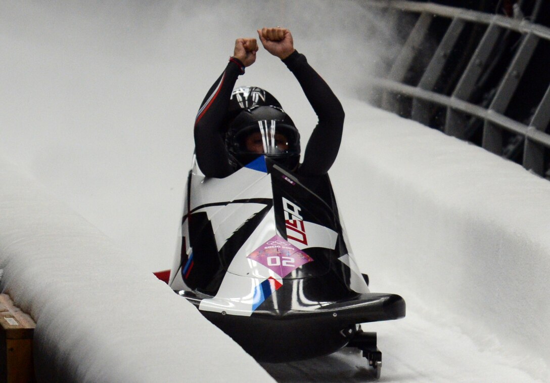 USA's Elana Meyers raises her arms in jublilation after crossing the finish line to earn an Olympic silver medal with a combined four-run time of 3:50.71, Feb. 19. Her teammate Lauren Williams applies the breaks as their bobsled approaches the stands.