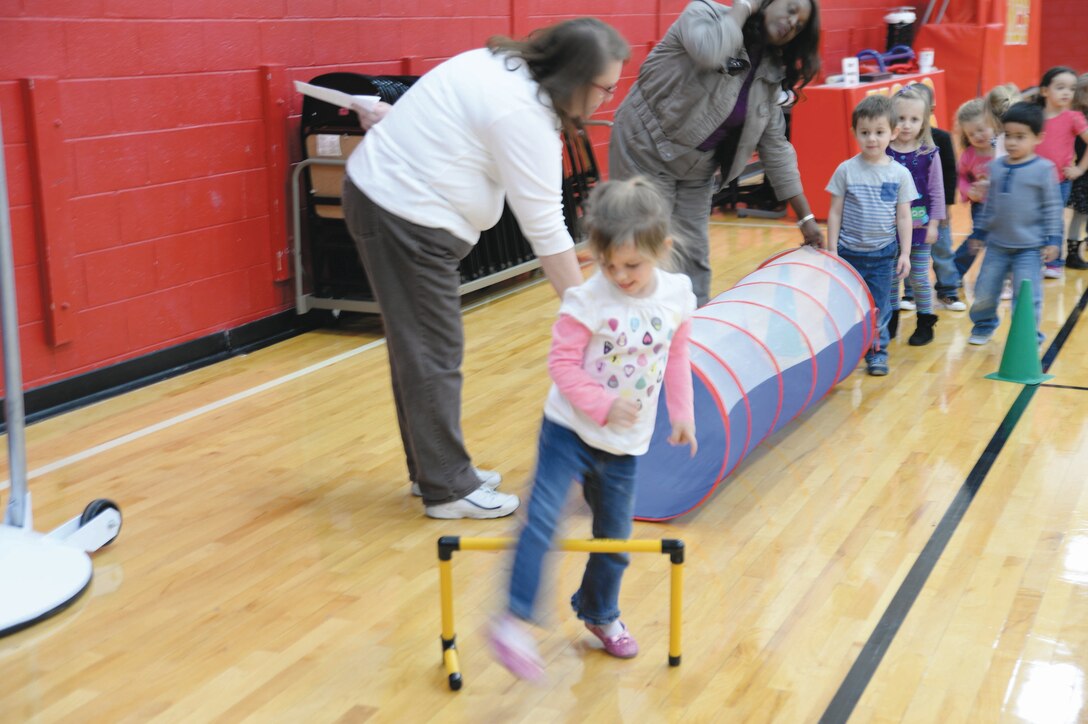 Children from the Child Development Center maneuver through the Obstacle Course, stepping over hurdles at the American Heart Association’s heart movement field day activity here, Feb. 13.