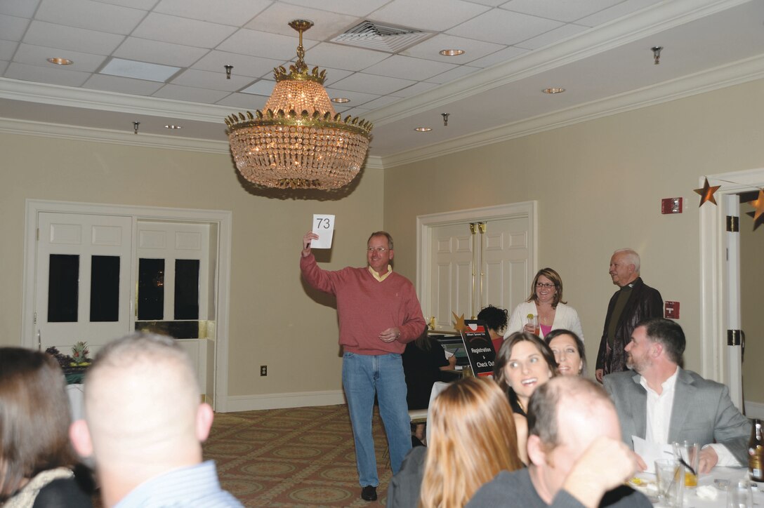 Chris McCarty, a local Albany resident, holds up his number to bid on items during the Officers’ Spouses Club annual auction held Saturday at Doublegate Country Club in Albany, Ga.