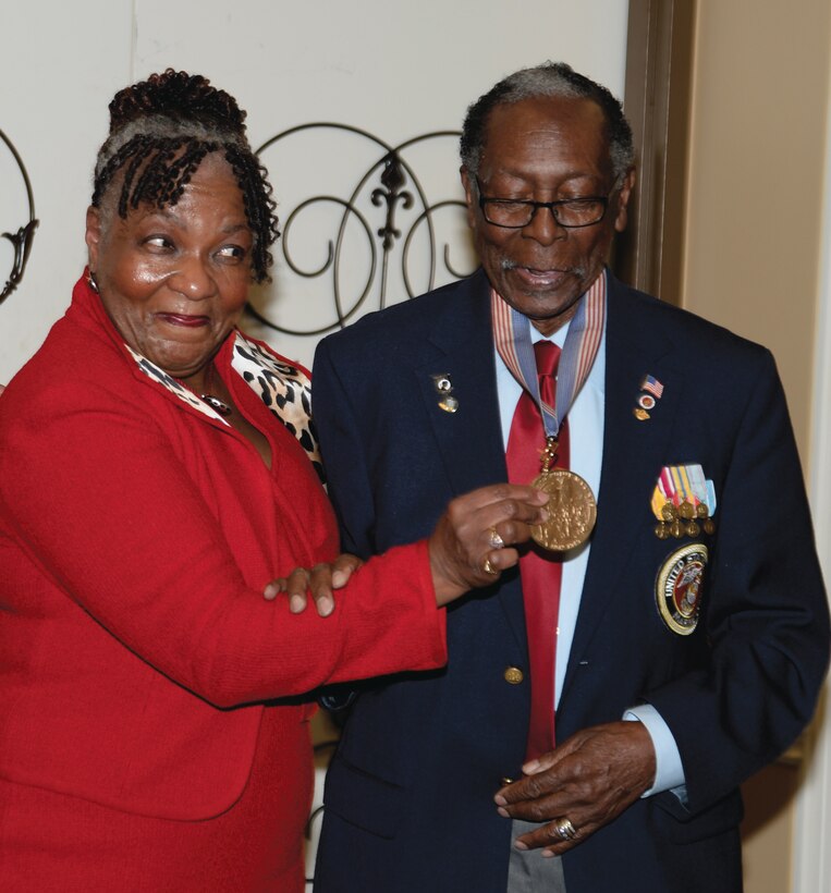 Marine Corps Logistics Base Albany’s Black History luncheon keynote speaker, Geraldine West Hudley (left), admires Montfort Point Marine, Henry Lee Jackson’s, Congressional Gold Medal, during the event at the Town and Country Restaurant, Feb. 11.