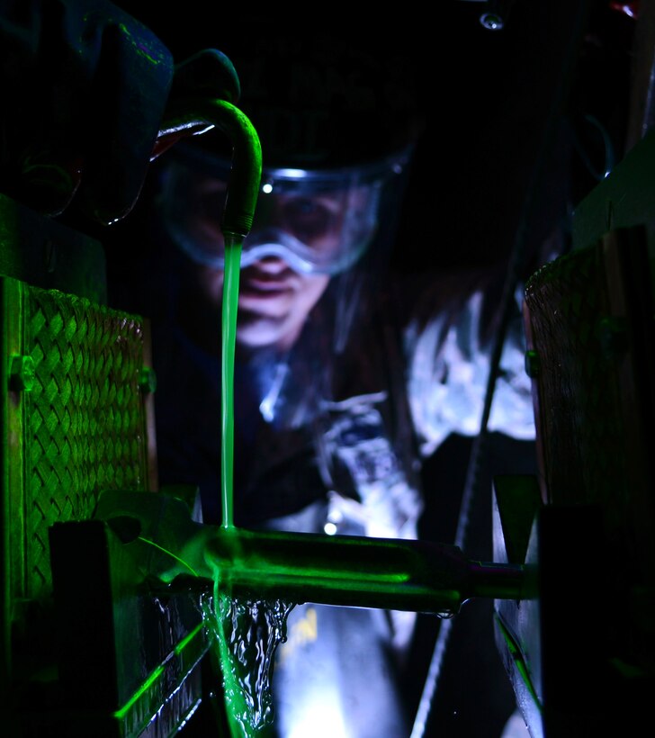 Tech. Sgt. Frank Castonguay pours a fluorescent oil bath over a KC-135 Stratotanker brake key inside a magnetic field generator Feb. 11, 2014, at Royal Air Force Mildenhall, England. The oil bath coats the part in fluorescent particles, which are attracted to any cracks after a magnetic field is established on either end of the part. This method quickly allows non-destructive inspection shop members to identify dangerous defects in parts. Castonguay is a 100th Maintenance Squadron NDI craftsman. (U.S. Air Force photo/Airman 1st Class Dillon Johnston)