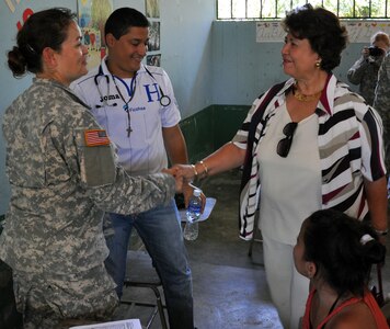 U.S. Army Spc. Lourdes Tarin greets Maria Luisa Martell de Matute, Vice-Mayor of Puerto Cortez during the vice-mayor's visit to an ongoing Medical Readiness and Training Exercise (MEDRETE) being conducted in the town of Caoba, Department of Cortes, Honduras, Feb. 20, 2014.  Several key leaders from Joint Task Force-Bravo met with Honduran military and civic leaders at the site to observe the medical relief mission and engage in discussion on how to build on the strong relationship between the U.S. and Honduras, and how Joint Task Force-Bravo can continue to partner with Honduras in order to provide assistance to those in need.  (U.S. Air Force photo by Capt. Zach Anderson)