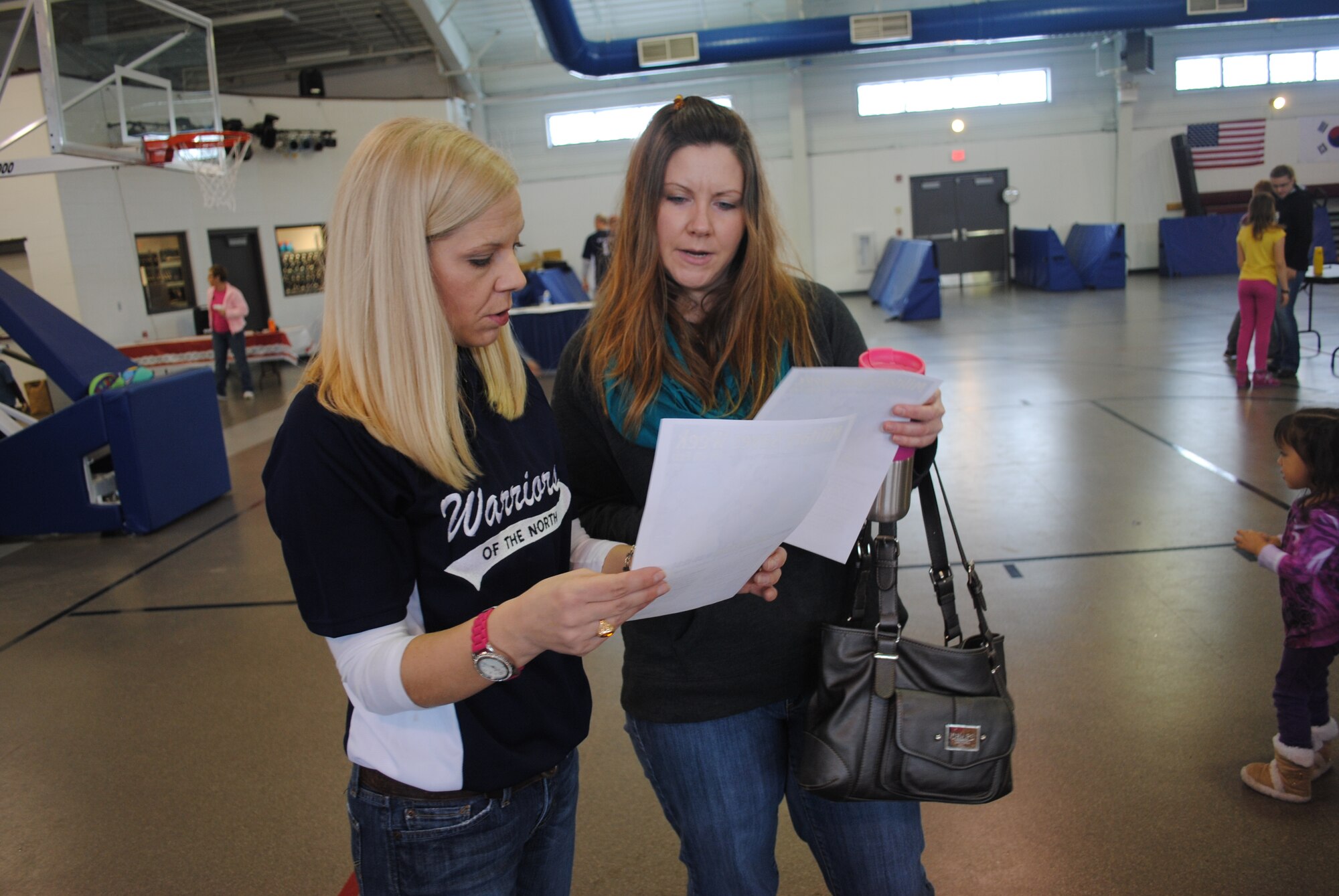 Key Spouses Group member Bonnie Bauman shows Amanda Cearley a list of 2014 Military Saves Week events during a financial information fair on Grand Forks Air Force Base on Feb. 20, 2014. Bauman and other members of the spouses group volunteered to serve as greeters, art activity facilitators and Military Saves Week promoters during the fair. (U.S. Air Force photo/Staff Sgt. Luis Loza Gutierrez)