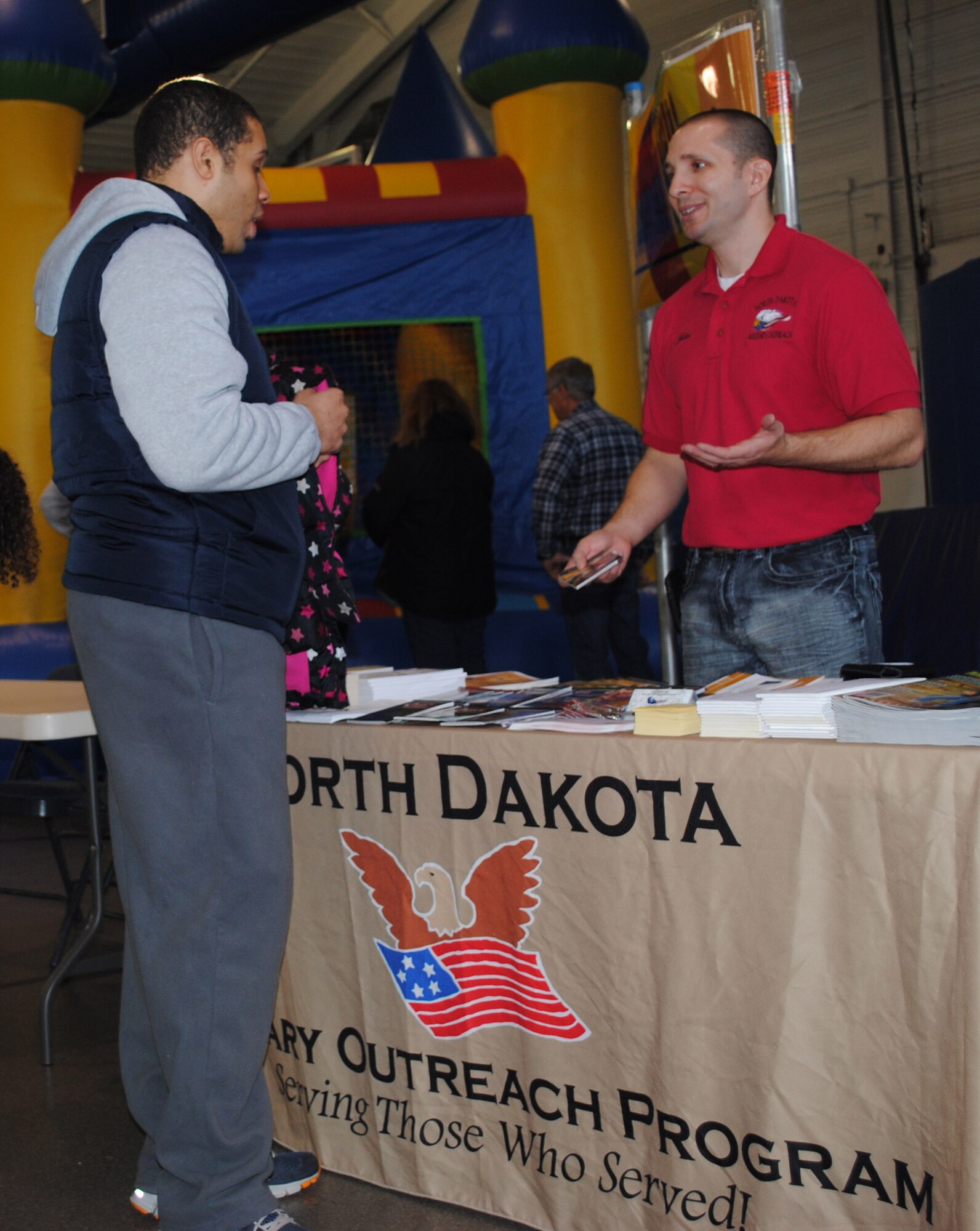 Military outreach specialist John Pitsiladis gives some information about services offered by the North Dakota Military Outreach Program to Senior Airman Javier Diaz Velazquez, 319th Communications Squadron, during the 2014 Financial Information Fair on Grand Forks Air Force Base, N.D., on Feb. 20, 2014. The fair kicked off this year's Military Saves Week on the base. (U.S. Air Force photo/Staff Sgt. Luis Loza Gutierrez)
