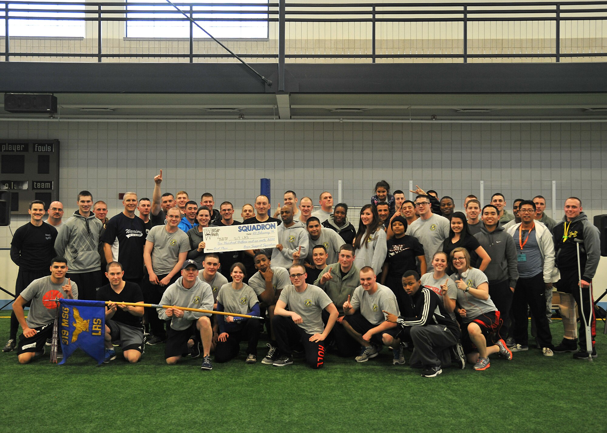 Col. Paul Bauman, 319th Air Base Wing commander (standing fourth from left), and Maj. Johari Hemphill, 319th Logistics Readiness Squadron commander (to right of check), pose for a photo with Airmen from the 319th LRS after they took first place in the team category in Winter Bash, Feb. 20, 2014, on Grand Forks Air Force Base, N.D. Winter Bash is an annual event designed to boost morale and increase espirt de corps. (U.S. Air Force photo/Senior Airman Xavier Navarro)