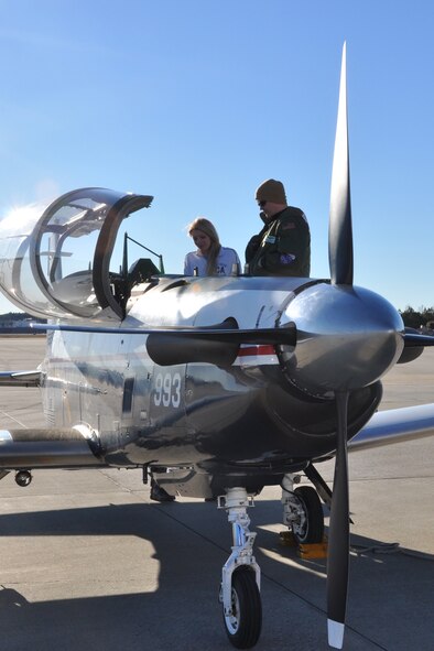 U.S. Navy Lt. Jordan Brown, pilot, Naval Air Station Pensacola, Fla., gives Brianna Van Gordon, Lassiter High School sophomore and JROTC cadet, a tour of a T-6B Texan II aircraft upon landing at Dobbins Air Reserve Base, Jan. 22. The T-6 Texan II is a tandem seat, turboprop trainer. Its primary mission is to train Navy and USMC pilots. Brown discussed opportunities in naval aviation with JROTC cadets. (U.S. Air Force photo/James Branch)