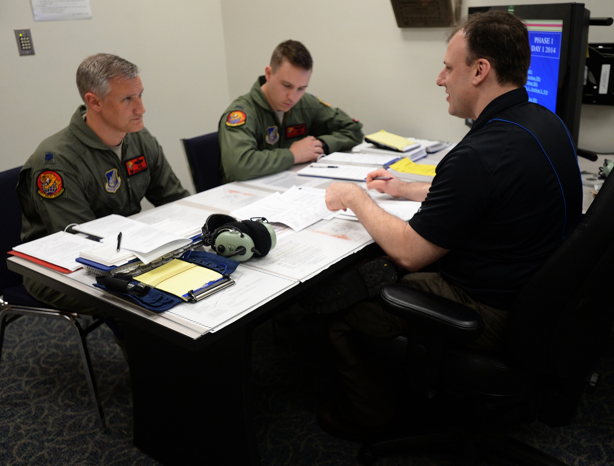Lt. Col. Gregg Johnson, 535th Airlift Squadron commander, and 1st Lt. Taylor Ragland, 535th AS pilot, receive a pre-training brief from Benjamin Slinkard, a C-17 Globemaster III pilot instructor, during a quarterly training session at Joint Base Pearl Harbor-Hickam, Hawaii, Feb. 18, 2014. Johnson and Ragland are C-17 pilots, and train extensively using a C-17 simulator, designed to give pilots a realistic feel for in-air tactical and emergency operations. (U.S. Air Force photo/Staff Sgt. Alexander Martinez)