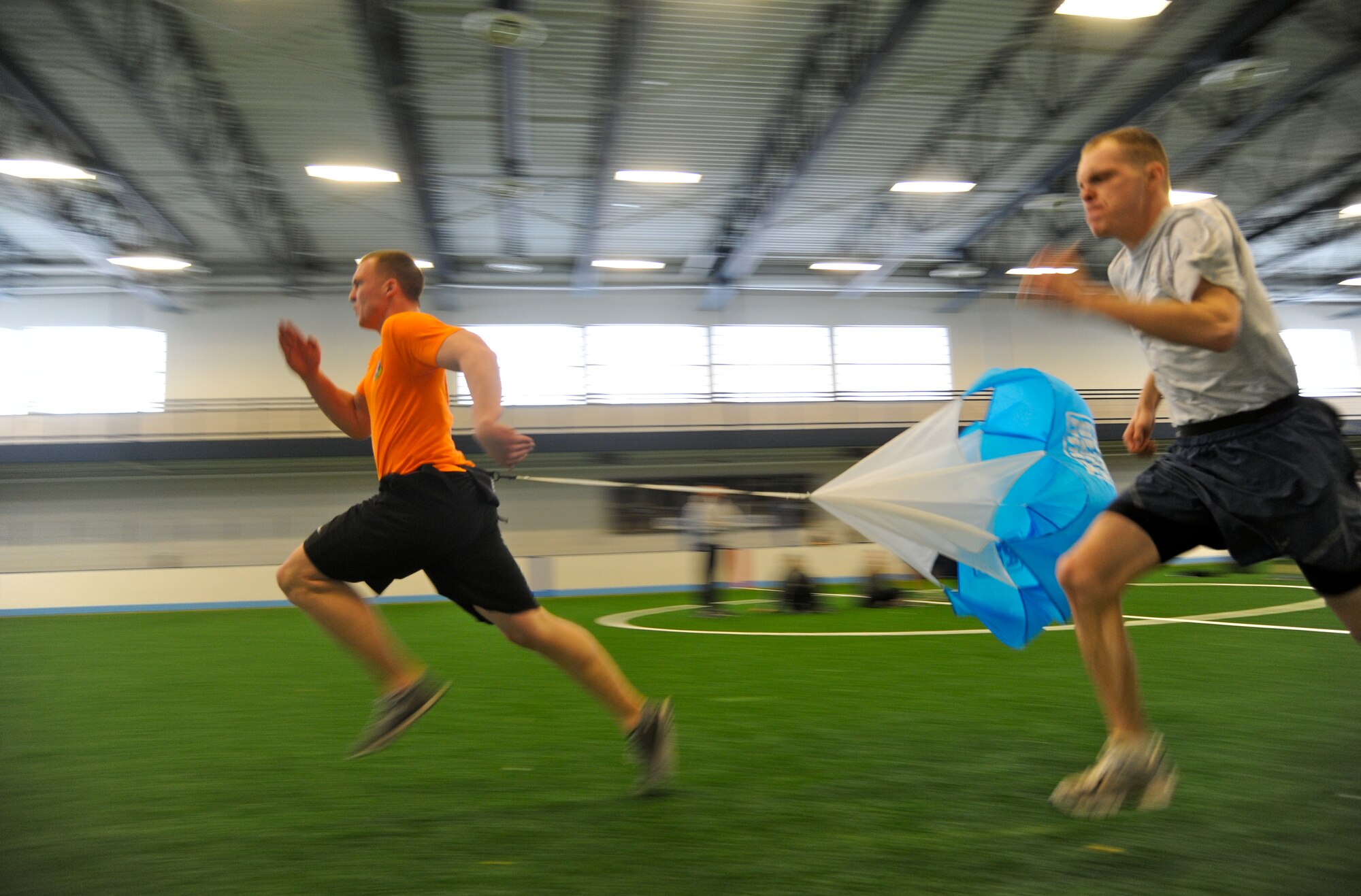 Two competitors blast through the Grand Forks Air Force Base Fitness Center field house during a parachute sprint competition at Winter Bash Feb. 20, 2014. Winter Bash, like its counterpart, Summer Bash, is an opportunity for Airmen take a break from day-to-day tasks in order to boost morale, unit cohesion and esprit de corps. (U.S. Air Force photo/Tim Flack)