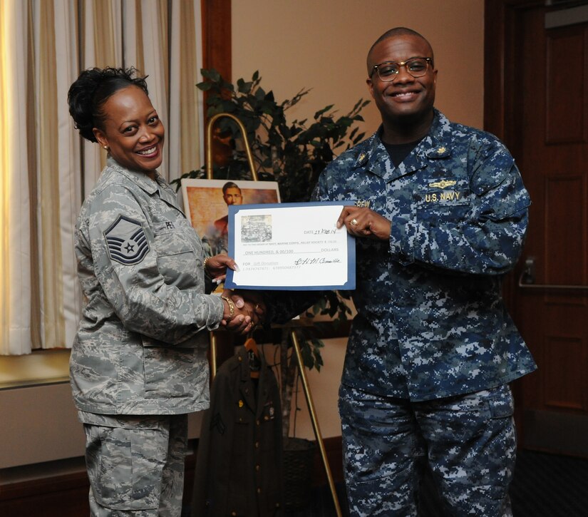 Master Sgt. Jannine D. Pete, 11th Wing Command Section superintendent, presents a charitable donation for the Navy Marine Corps. Relief Society to Lt. Cmdr. Bryan Pettigrew at a luncheon held at the club at Joint Base Andrews, Md. on Feb. 19, 2014. The donation was from the JBA Black History Month Committee. Pettigrew, Navy Information Dominance Corps., Region of Washington, D.C. assistant officer in charge, was the guest speaker for the event. (U.S. Air Force photo/Airman 1st Class Ryan J. Sonnier)