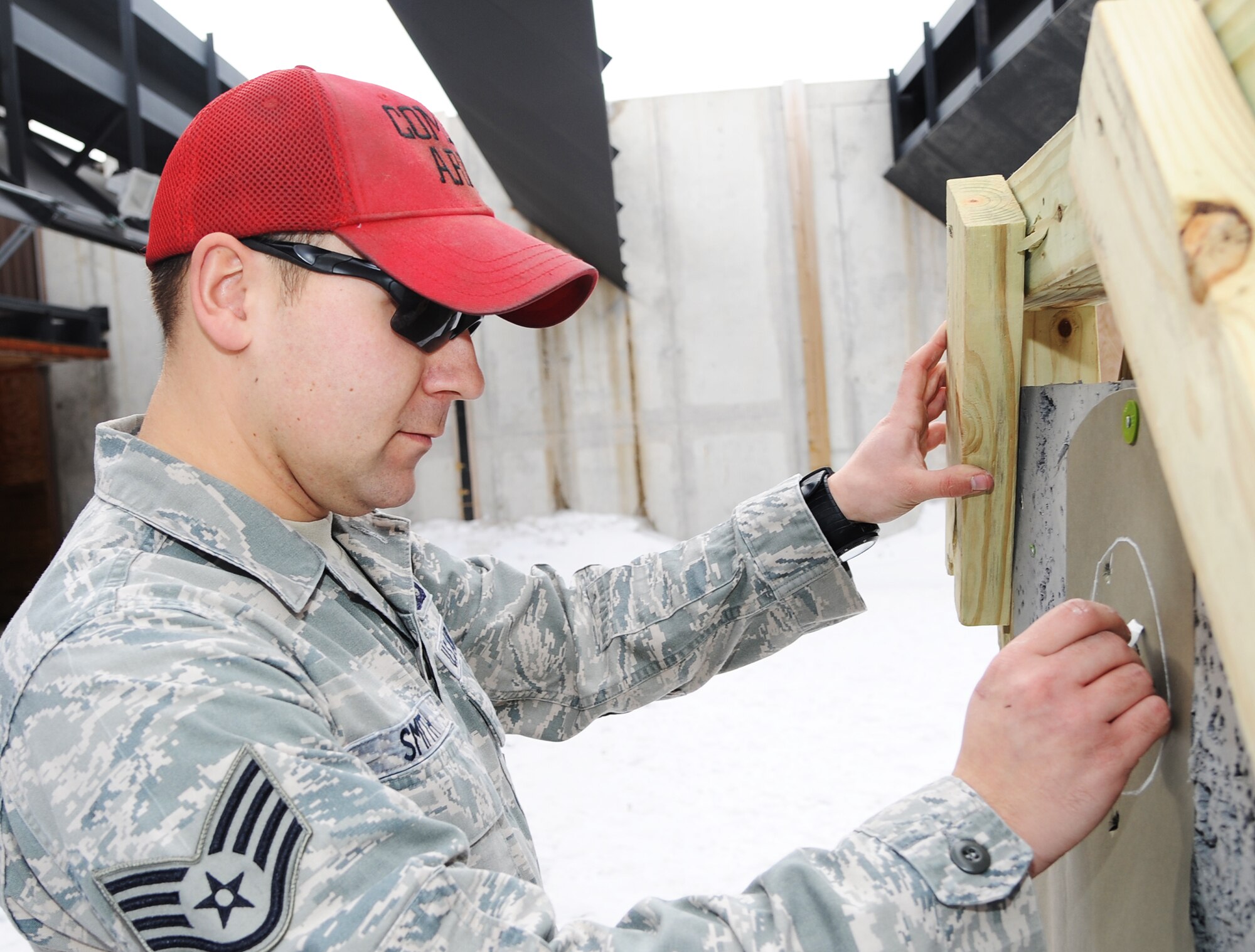 Staff Sgt. Jeremy Smith, 5th Security Forces Combat Arms Training instructor, scores a qualification target at Minot Air Force Base N.D., Feb. 19, 2014. Smith, along with other instructors, trains individuals prepping for deployments and needing qualifications for a variety of weapons systems. (U.S. Air Force photo/Senior Airman Andrew Crawford)