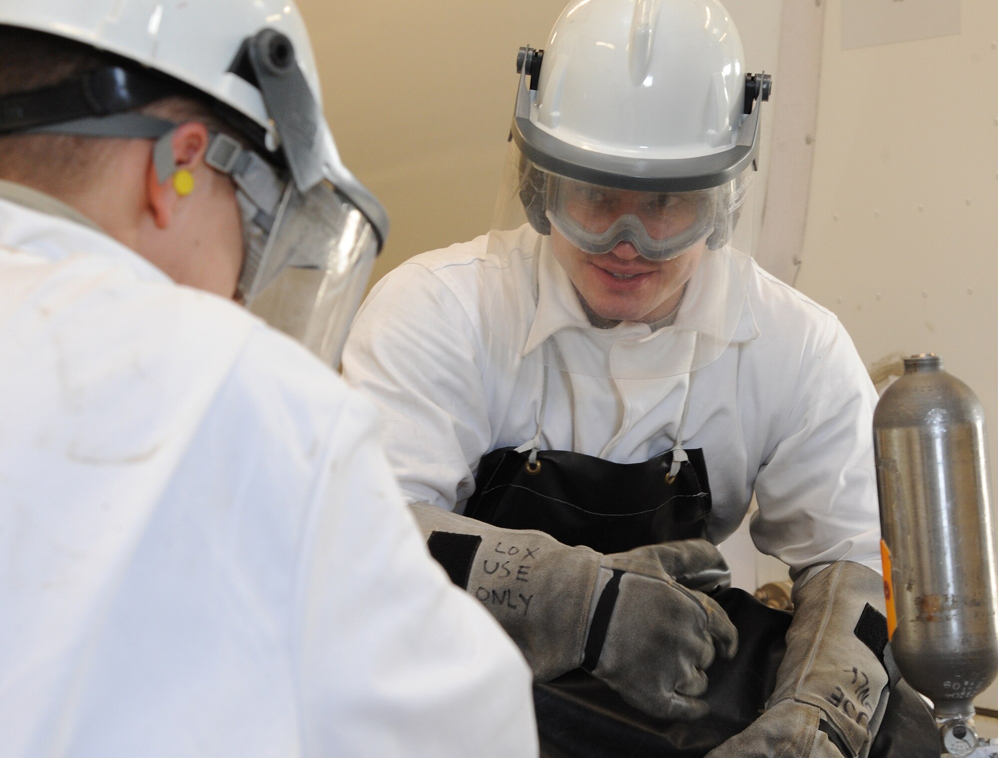 Senior Airman Cole Peck, 5th Logistics Readiness Squadron fuels laboratory technician, explains the procedure of extracting liquid oxygen to Senior Airman Cole Peck, 5th LRS fuels laboratory technician. During the procedure Peck and Dicken follow a checklist to extract the sample safely and effectively. (U.S. Air Force photo/Senior Airman Andrew Crawford)

