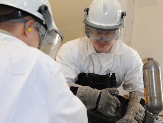 Senior Airman Cole Peck, 5th Logistics Readiness Squadron fuels laboratory technician, explains the procedure of extracting liquid oxygen to Senior Airman Cole Peck, 5th LRS fuels laboratory technician. During the procedure Peck and Dicken follow a checklist to extract the sample safely and effectively. (U.S. Air Force photo/Senior Airman Andrew Crawford)

