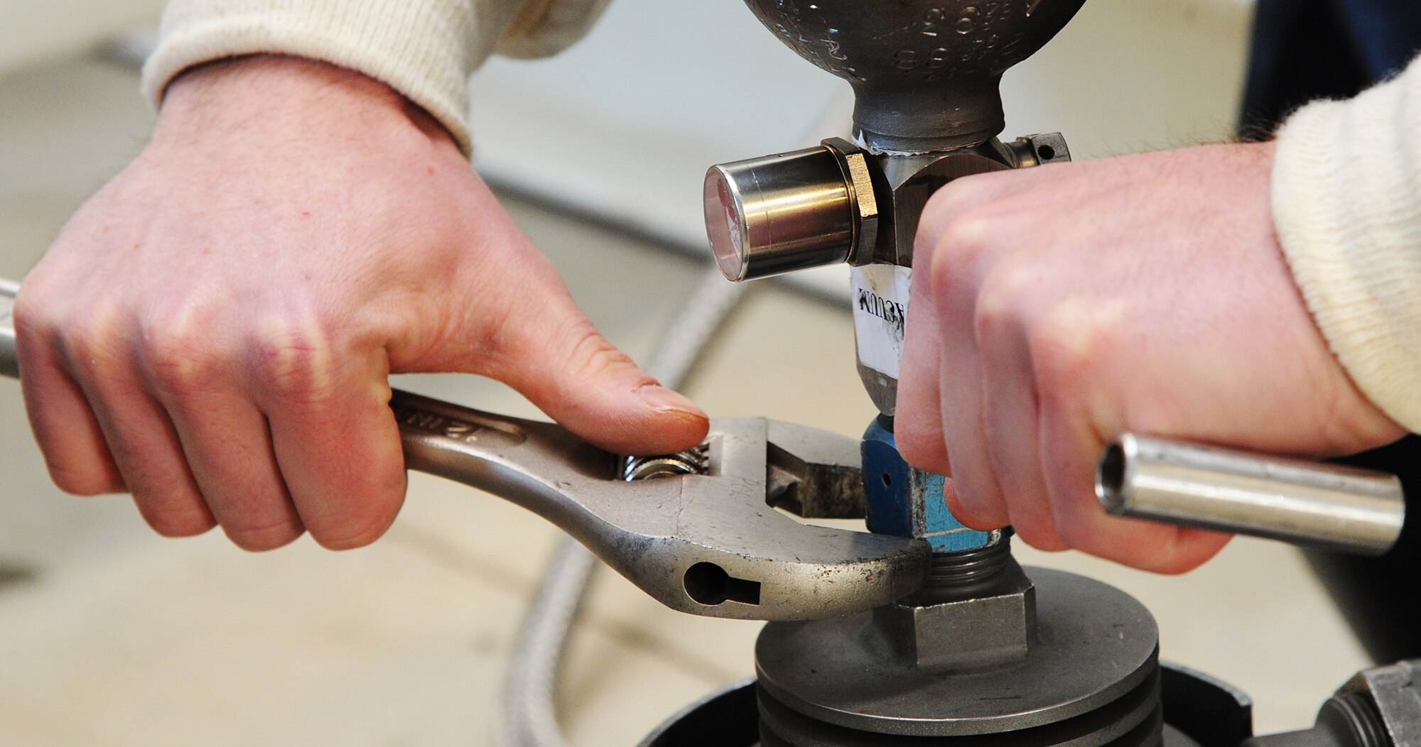 Senior Airman Cole Peck, 5th Logistics Readiness Squadron base fuels laboratory technician, tightens a bolt used to connect a canister to a machine that collects samples of liquid oxygen from a tank at the new Cryogenics Facility to be sent to Wright Patterson Air Force Base, Ohio for analysis. Peck extracts samples from a tank at the new cryogenics facility to send out to be tested. (U.S. Air Force photo/Senior Airman Andrew Crawford)