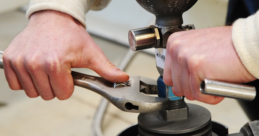 Senior Airman Cole Peck, 5th Logistics Readiness Squadron base fuels laboratory technician, tightens a bolt used to connect a canister to a machine that collects samples of liquid oxygen from a tank at the new Cryogenics Facility to be sent to Wright Patterson Air Force Base, Ohio for analysis. Peck extracts samples from a tank at the new cryogenics facility to send out to be tested. (U.S. Air Force photo/Senior Airman Andrew Crawford)