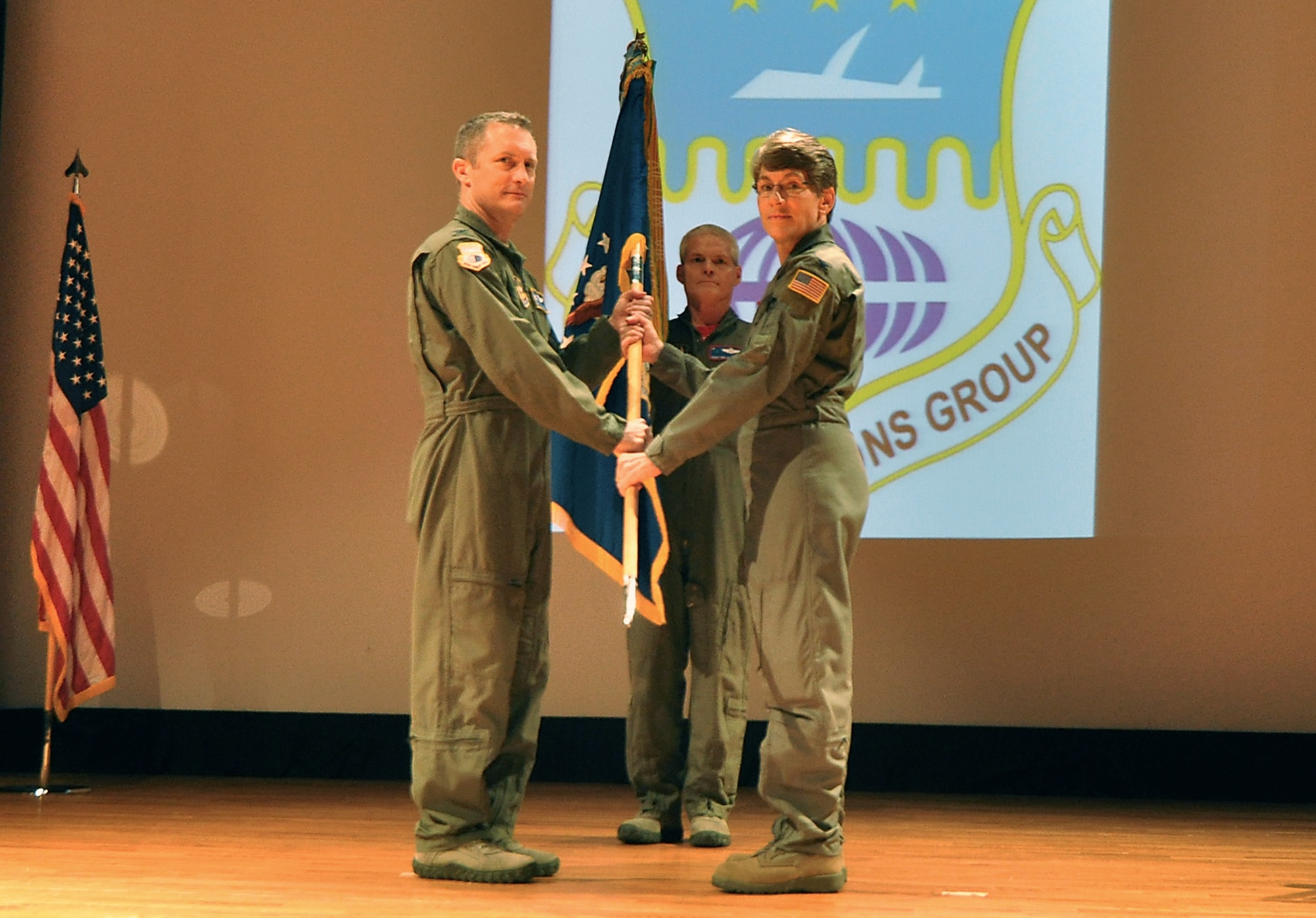 Col. James Fontanella, 315th Airlift Wing commander passes the 315th Operations Group guideon to Col. Caroline Evernham during an assumption of command ceremony at Joint Base Charleston Feb. 21. Chief Master Sgt, Ben Alexander, 701st Airlift Squadron, stand by behind them. (U.S. Air Force Reserve photo by Michael Dukes)
